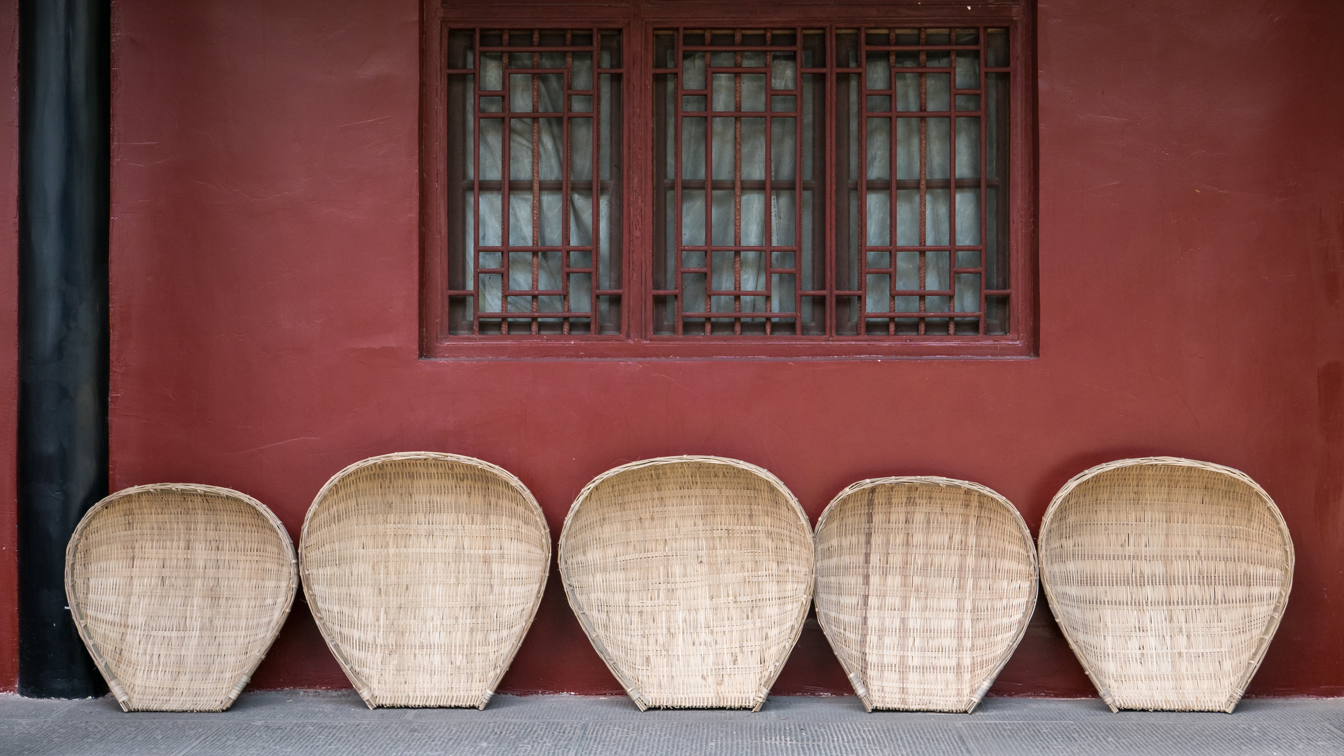 a row of wicker baskets in front of a red wall