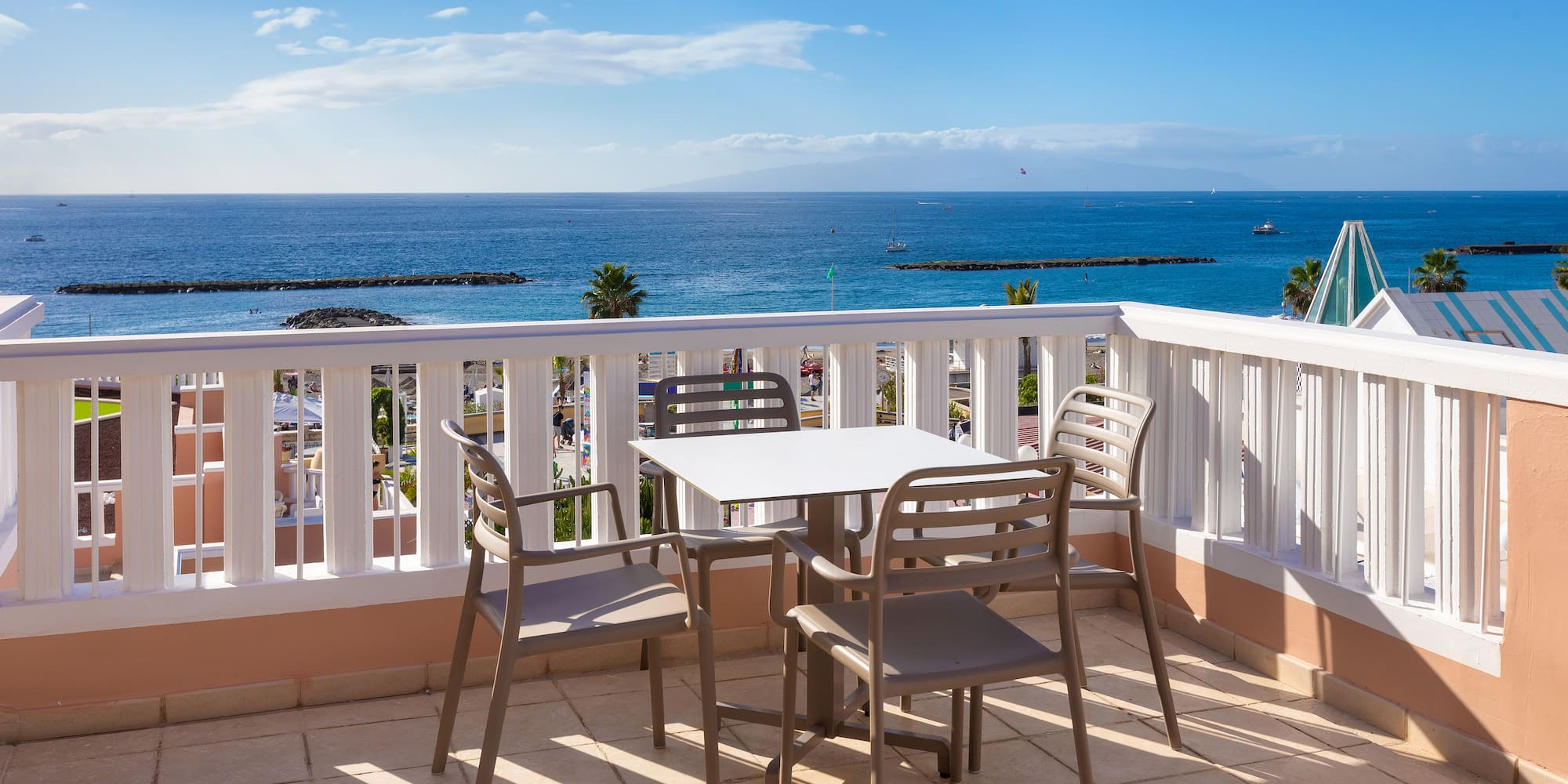 a table and chairs on a balcony overlooking the ocean