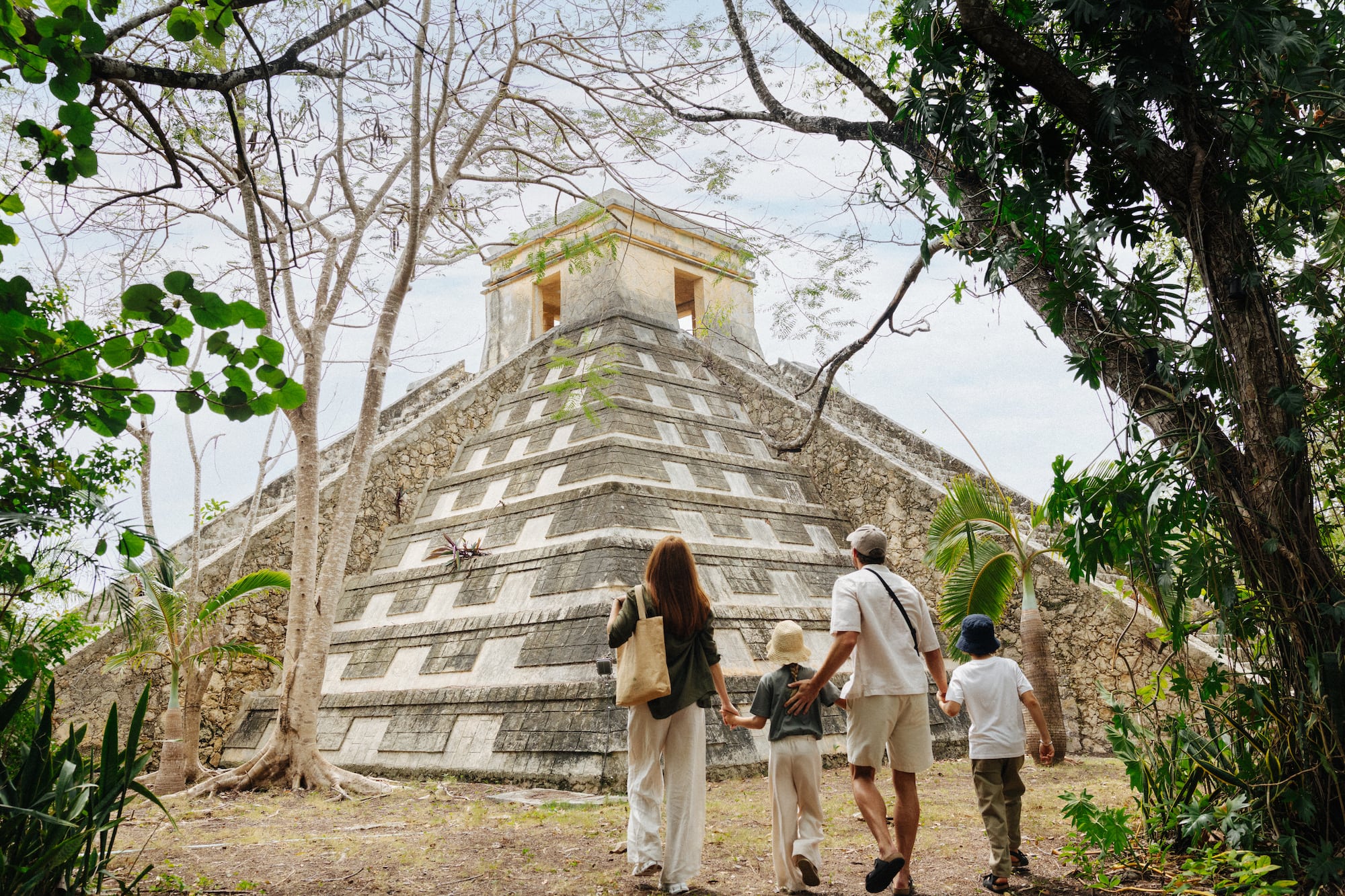 Familia explorando pirámide maya antigua en la selva, México.