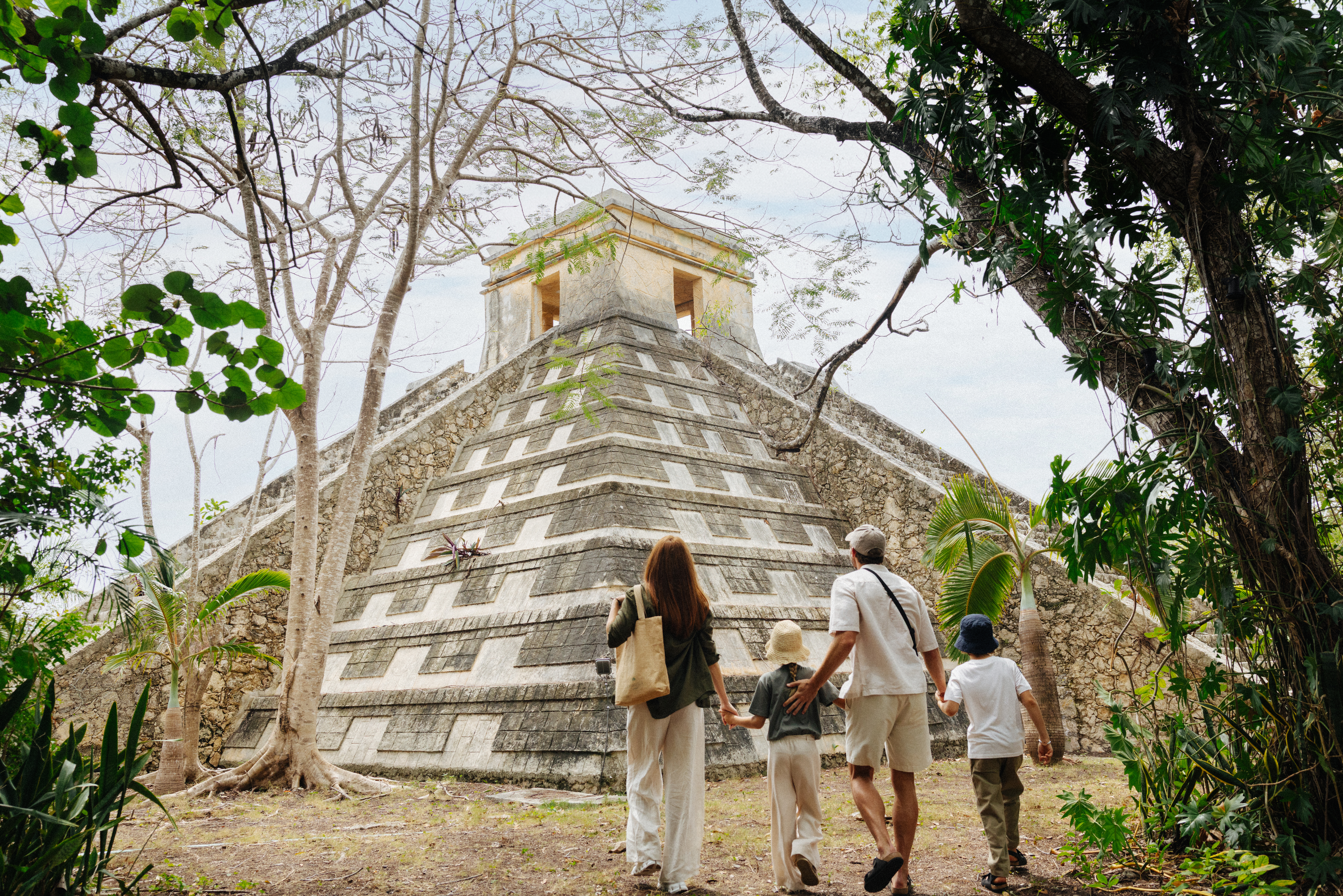Familia explorando pirámide maya antigua en la selva, México.