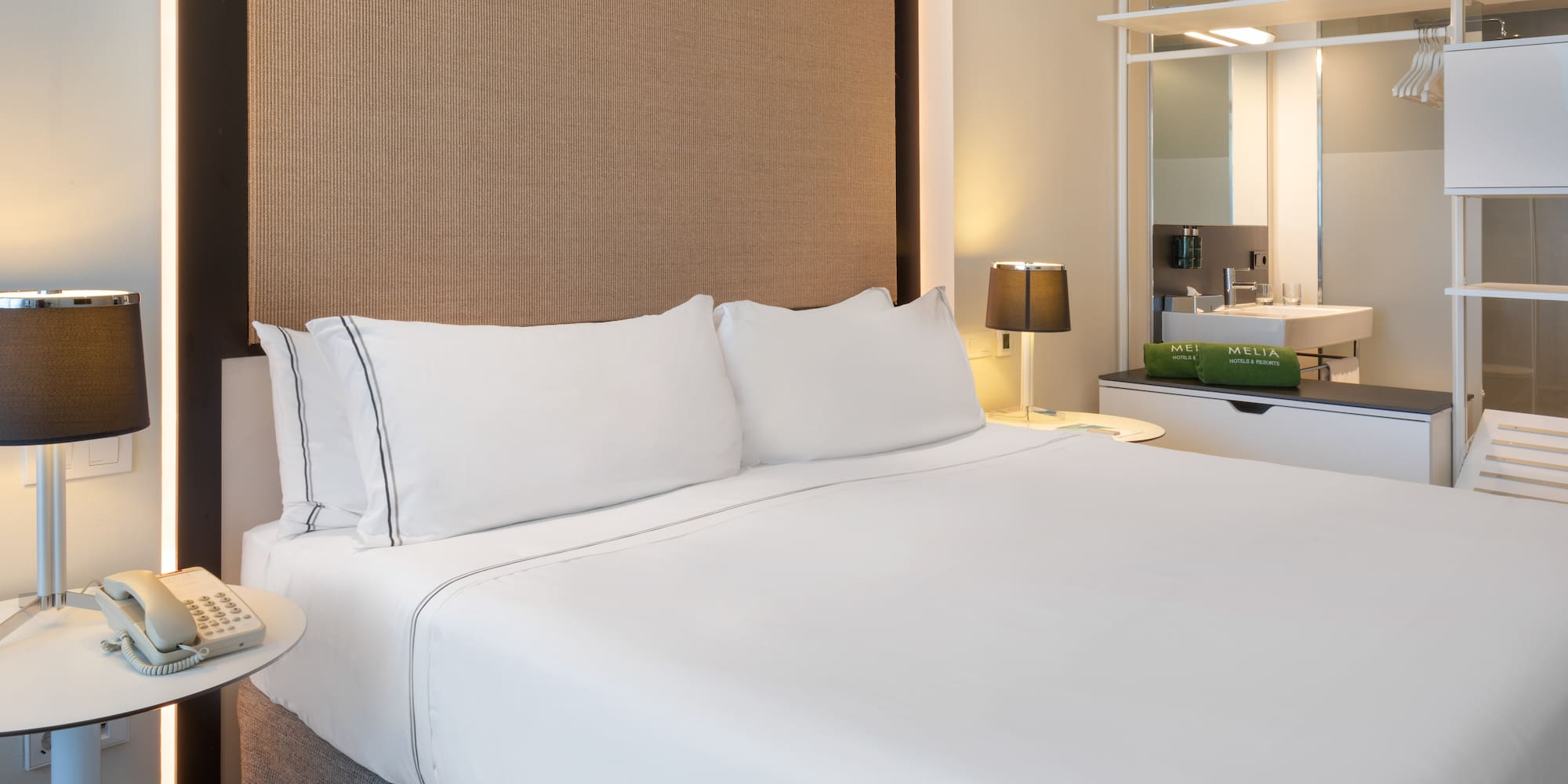 a bed with white sheets and a brown headboard