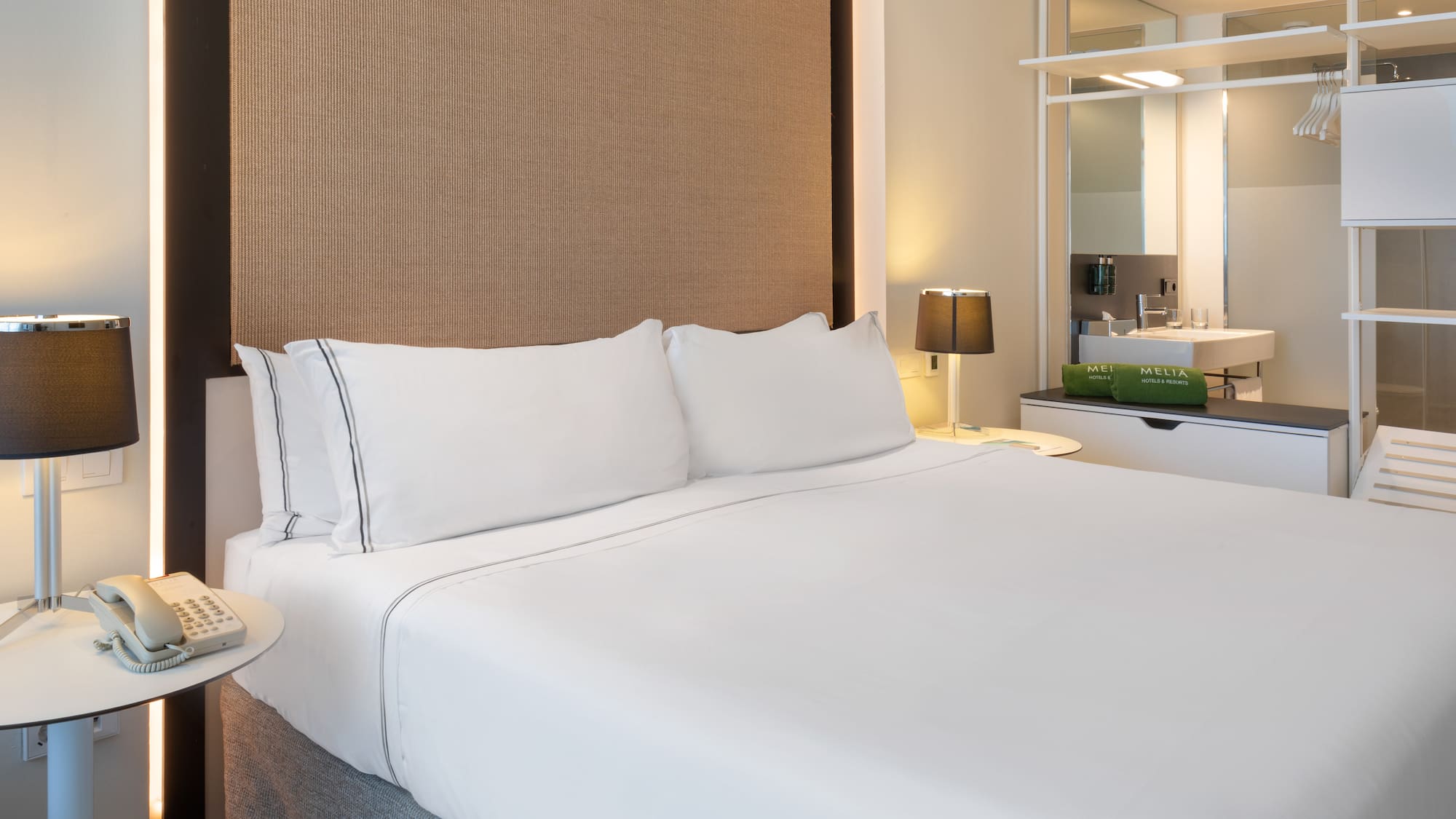 a bed with white sheets and a brown headboard