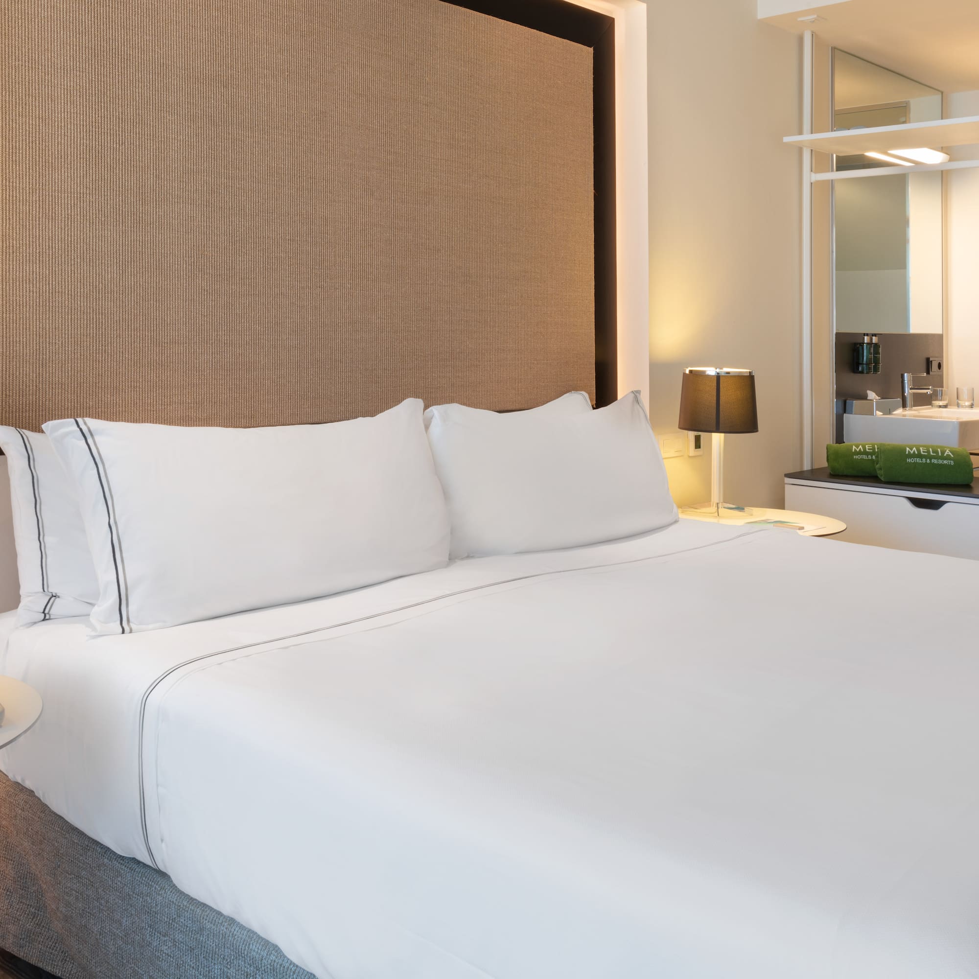 a bed with white sheets and a brown headboard