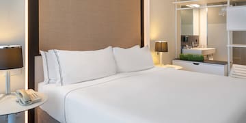 a bed with white sheets and a brown headboard