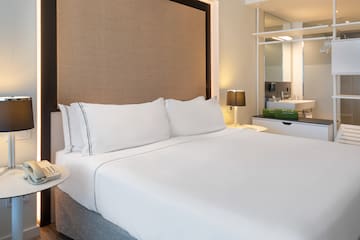 a bed with white sheets and a brown headboard