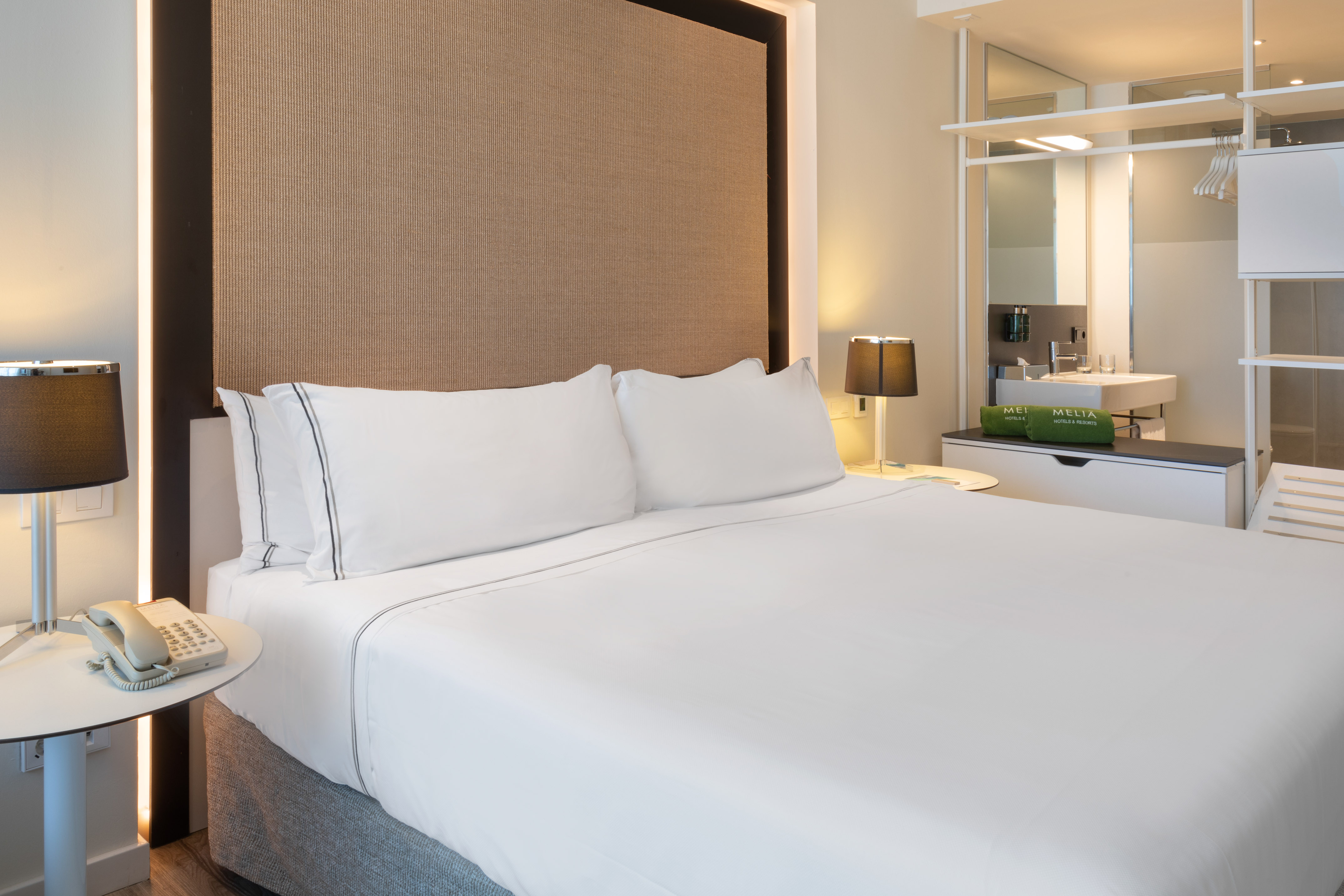 Modern Meliá hotel room with large bed, textured headboard, and clean design.