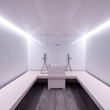 a white room with a bench and a bucket of water