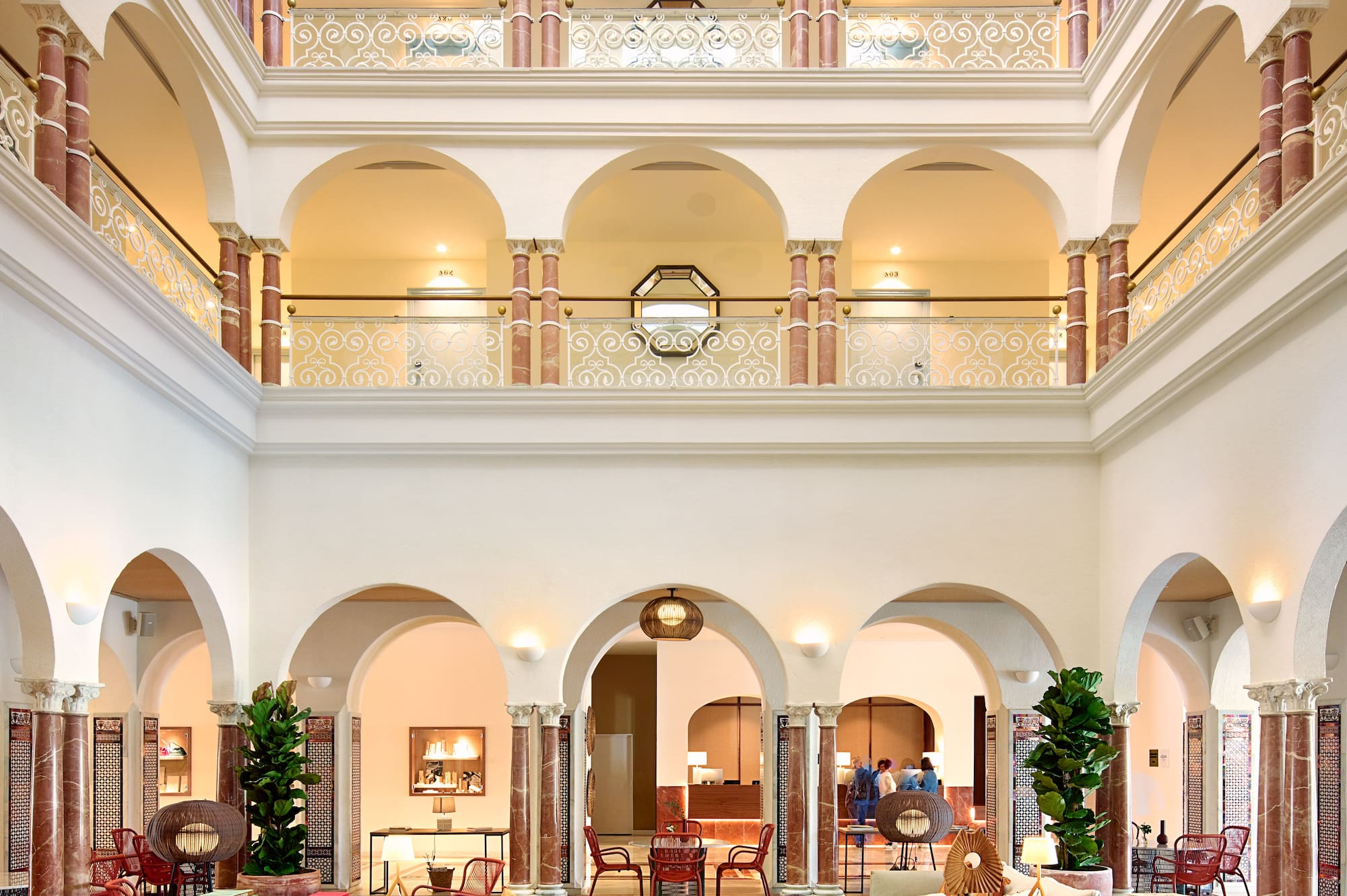 Elegant hotel atrium with multi-story arches, marble columns, and a modern lounge.