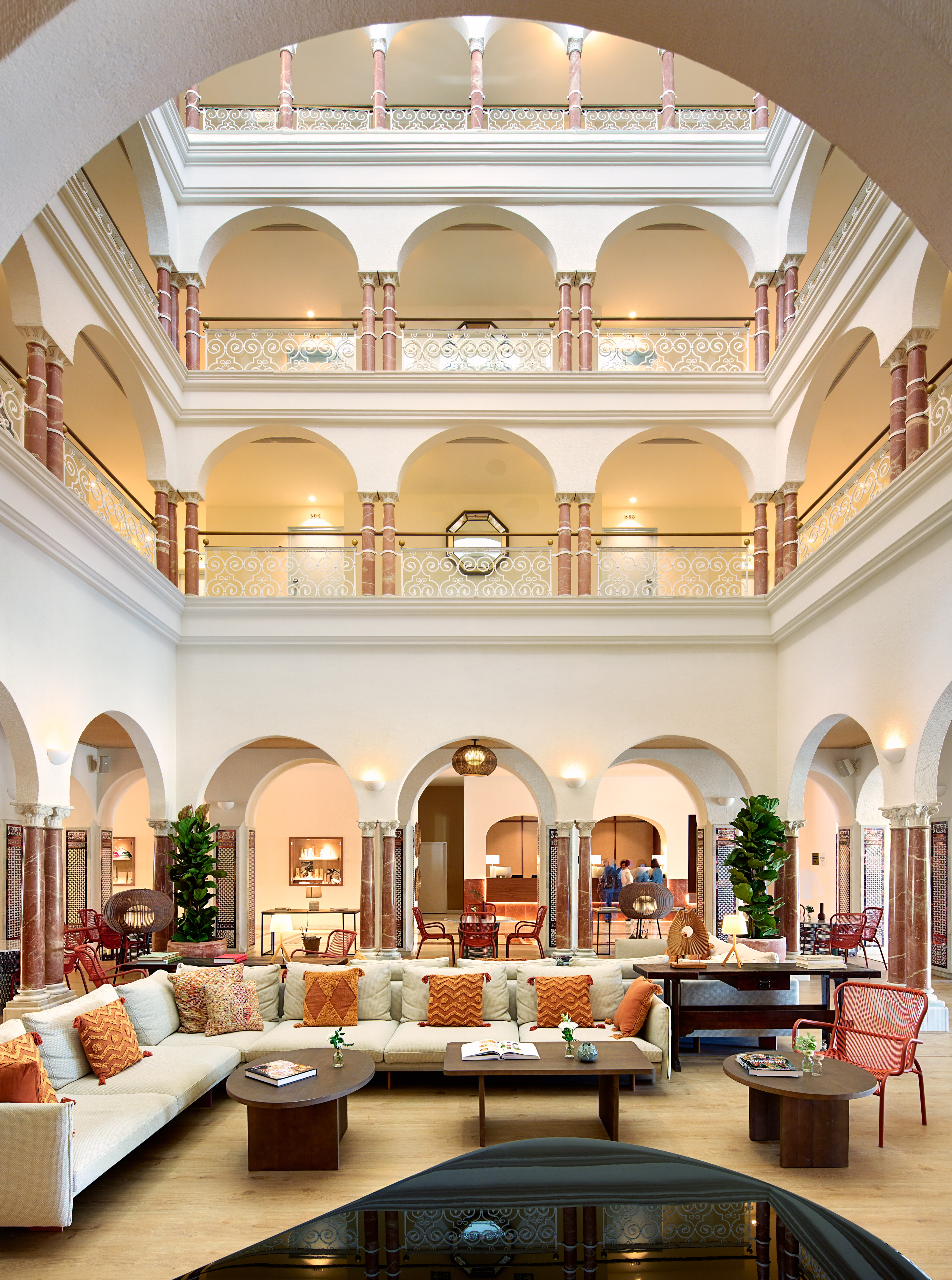 Elegant hotel atrium with multi-story arches, marble columns, and a modern lounge.