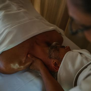 a man lying on a bed with his neck