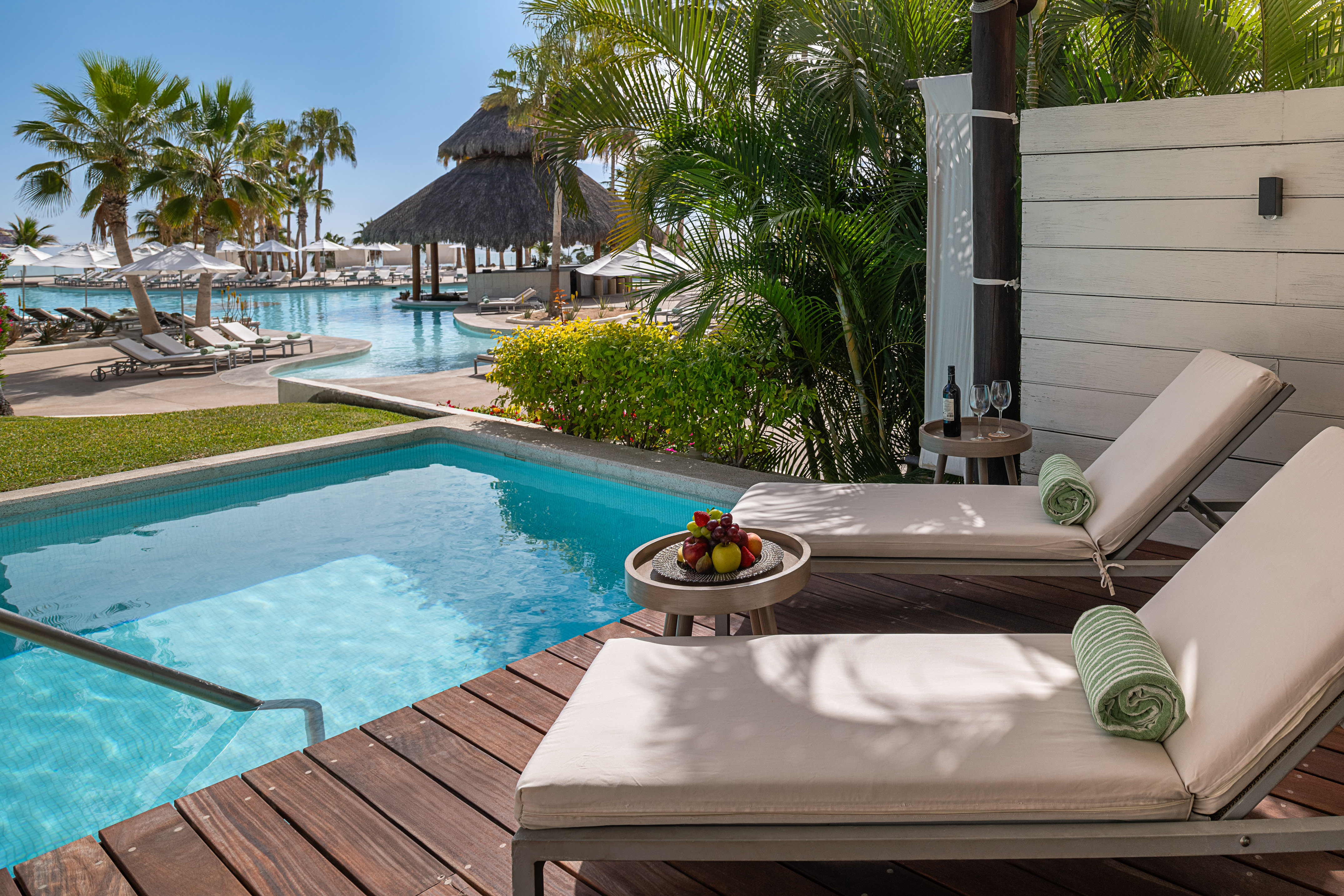 Private plunge pool, lounge chairs on deck, tropical resort view.