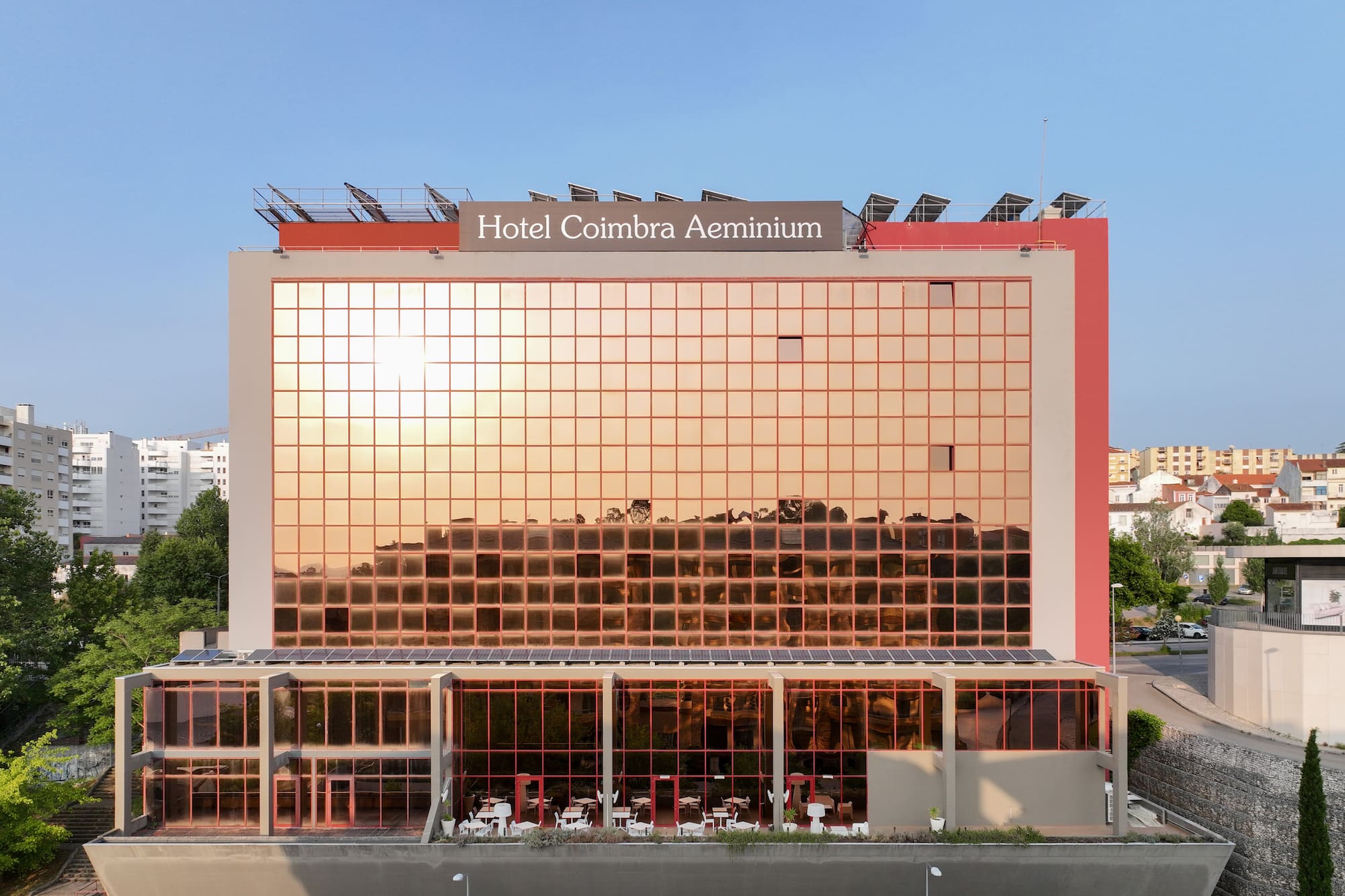 Hotel Coimbra Aeminium, modern hotel with golden glass facade and solar panels.