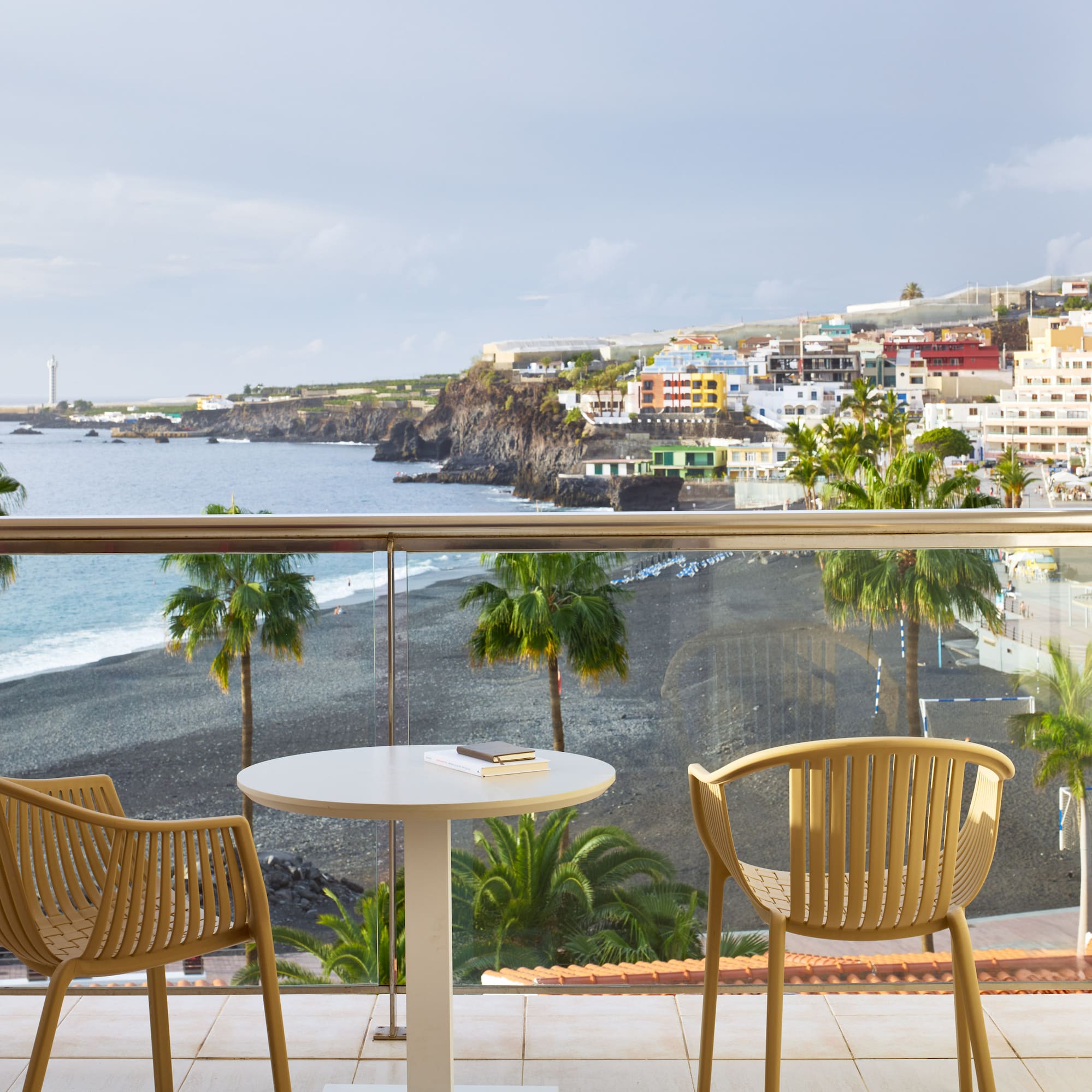 a table and chairs on a balcony overlooking a beach