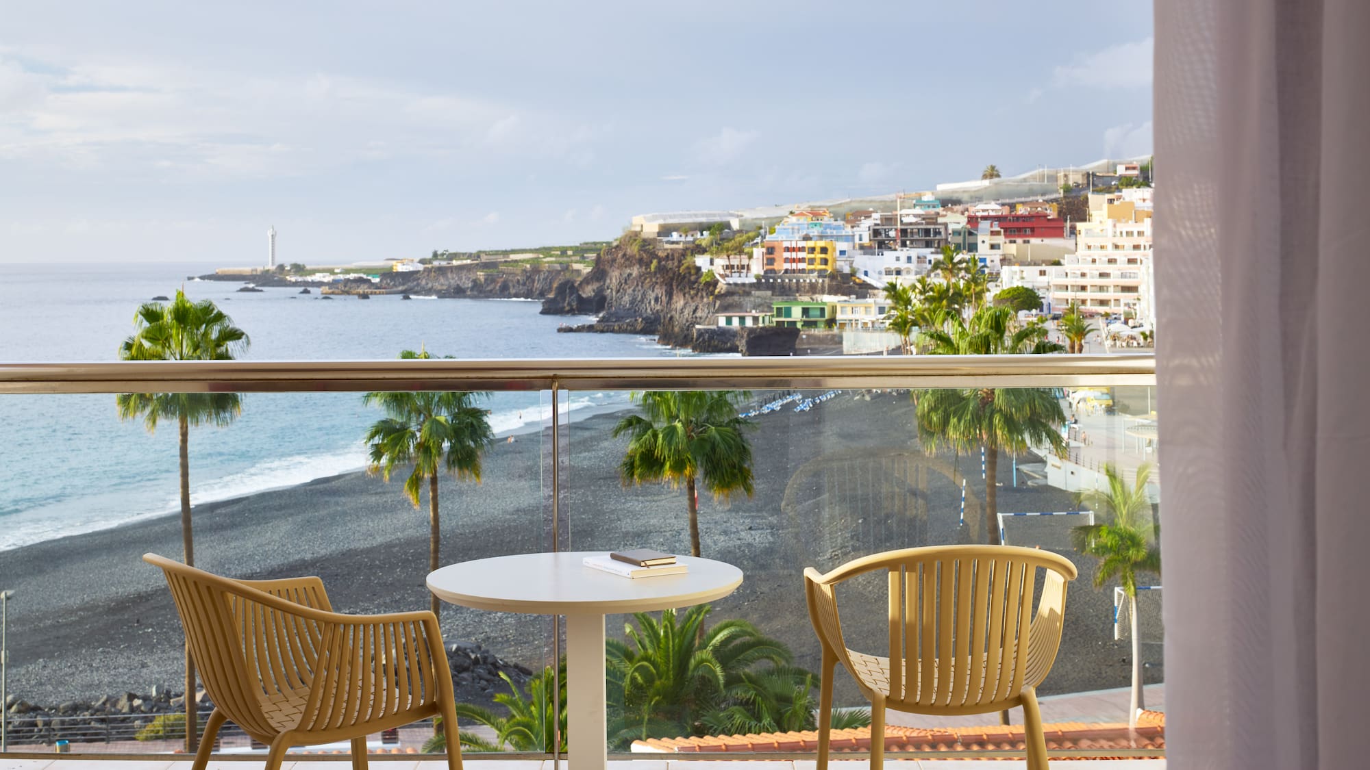 a table and chairs on a balcony overlooking a beach