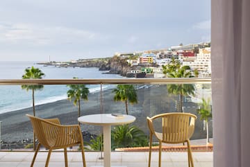 a table and chairs on a balcony overlooking a beach