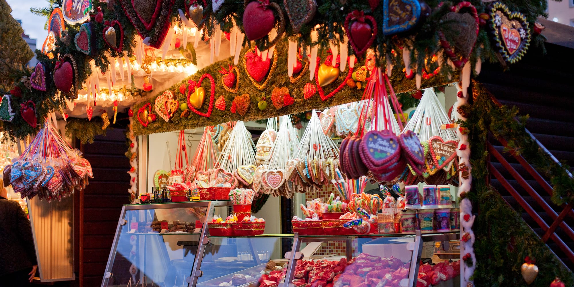 Christmas market stall with gingerbread hearts, sweets, and festive lights.