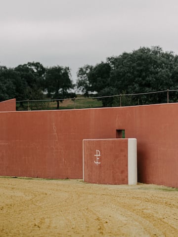 a red wall with a white square object on it with Royal Palaces of Abomey in the background