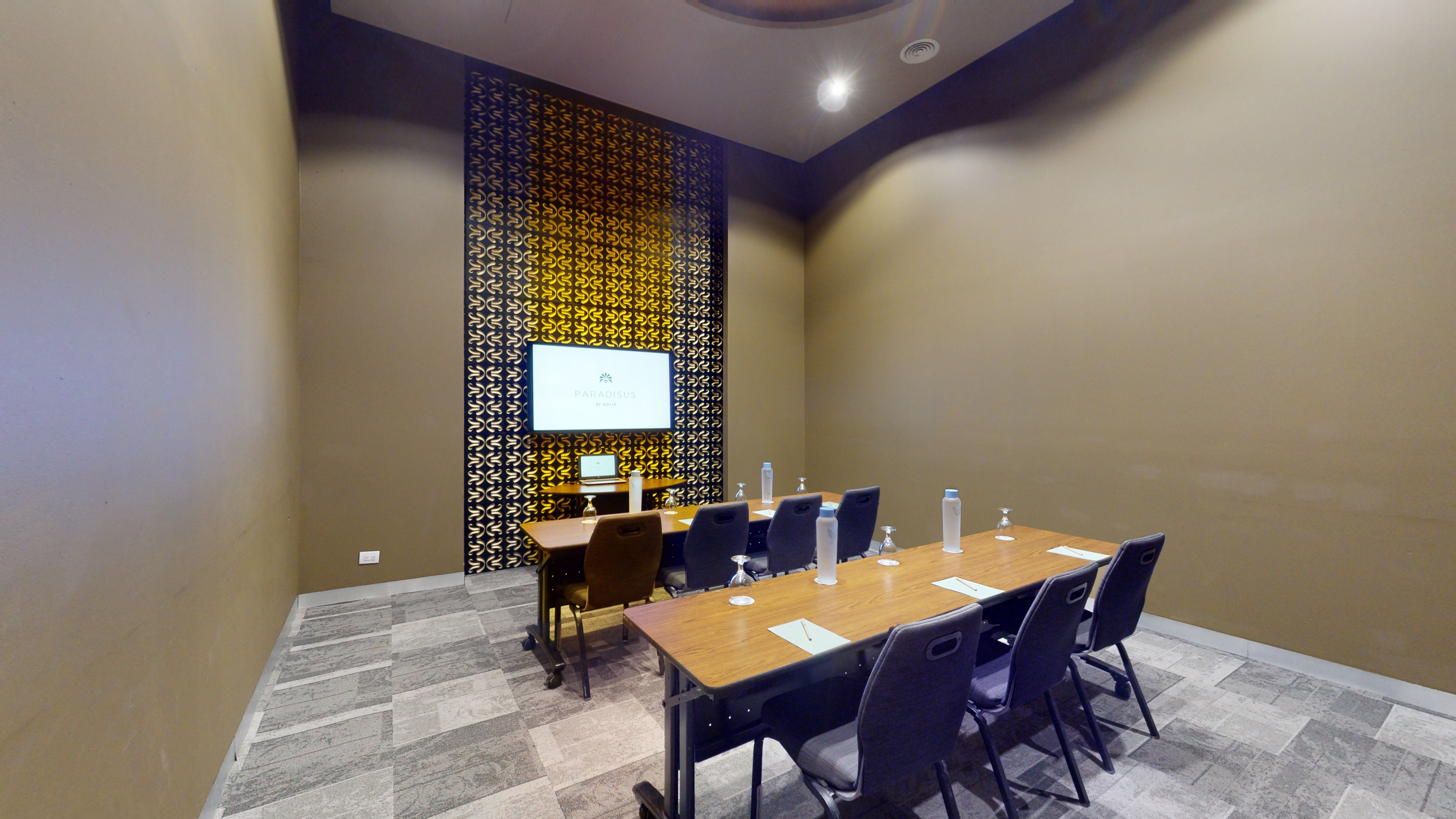 Modern meeting room with presentation screen, long table, and chairs.