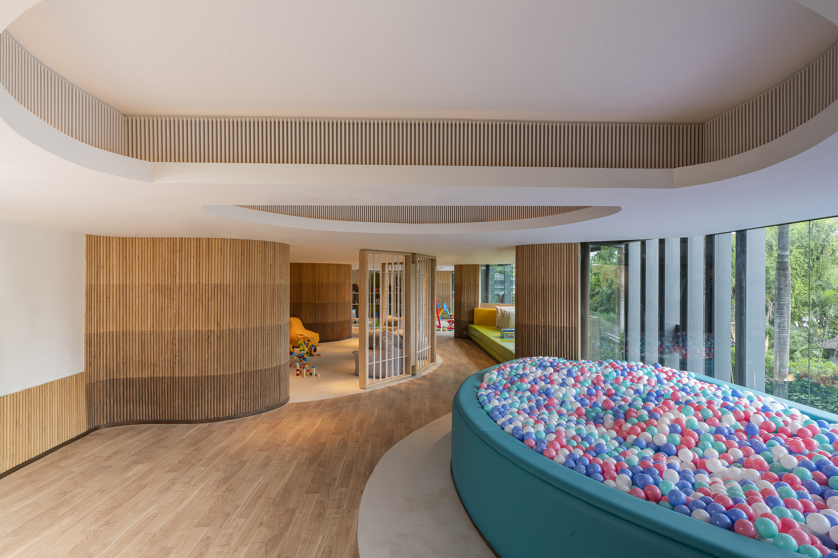 Modern playroom with vibrant ball pit, wood walls, and natural light.