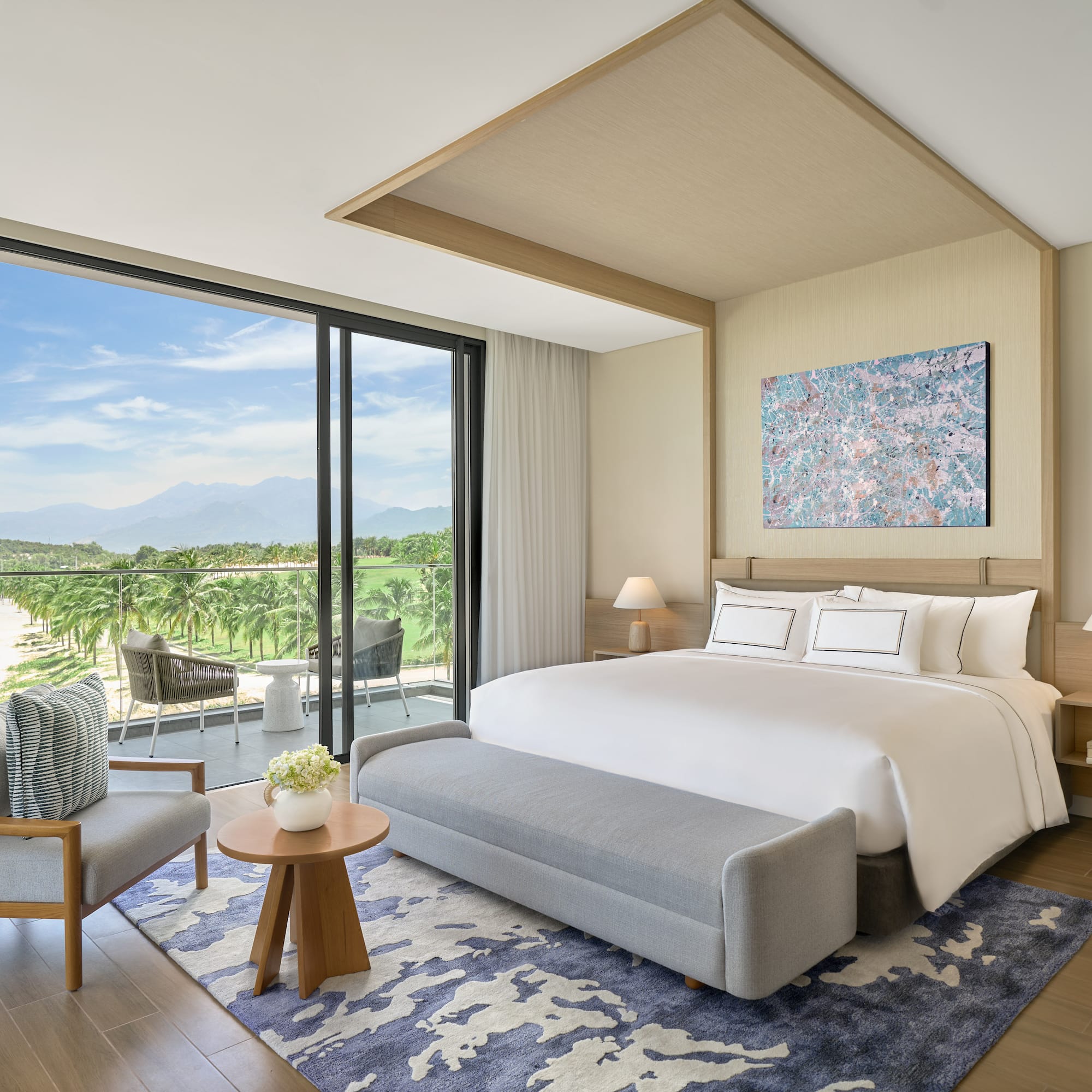 Modern luxury bedroom with balcony overlooking golf course and mountains.