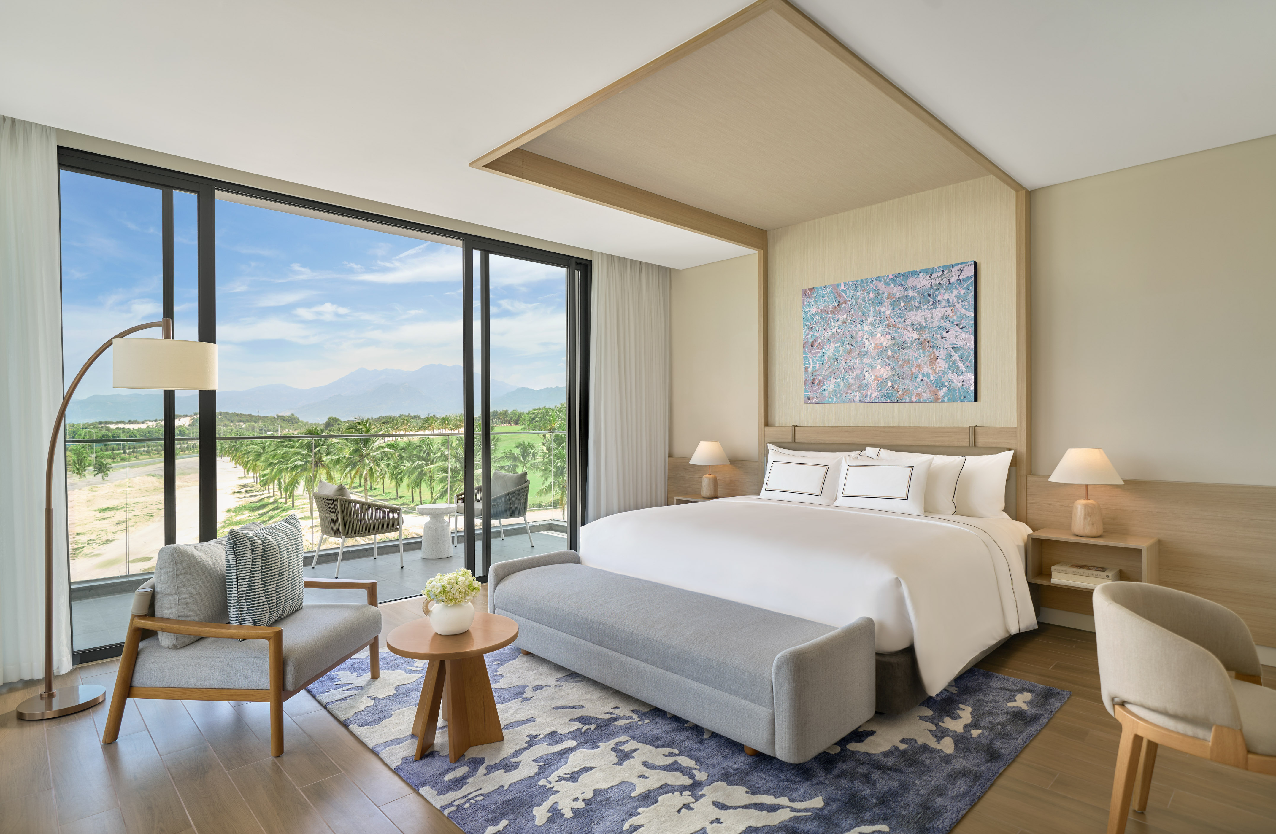 Modern luxury bedroom with balcony overlooking golf course and mountains.