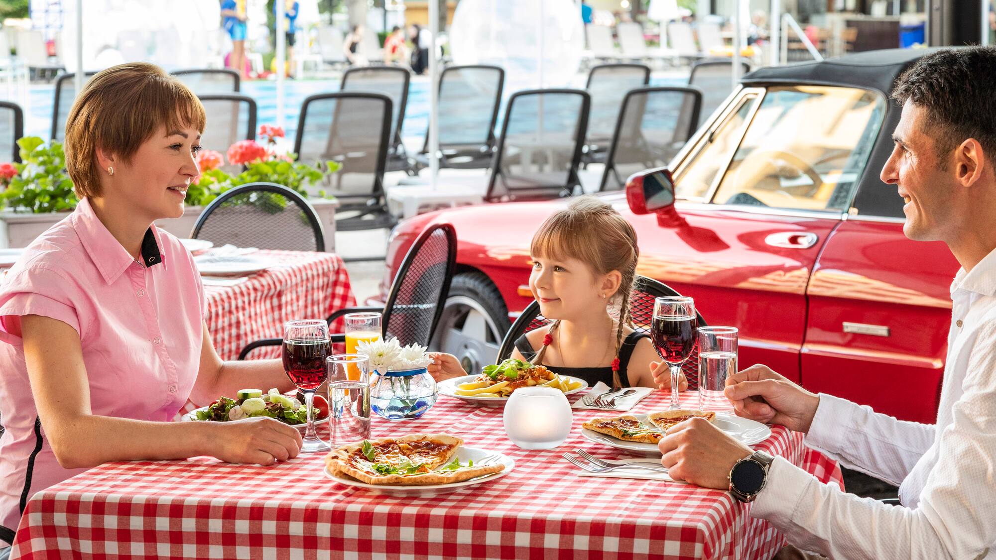 a man and woman sitting at a table with a girl eating pizza