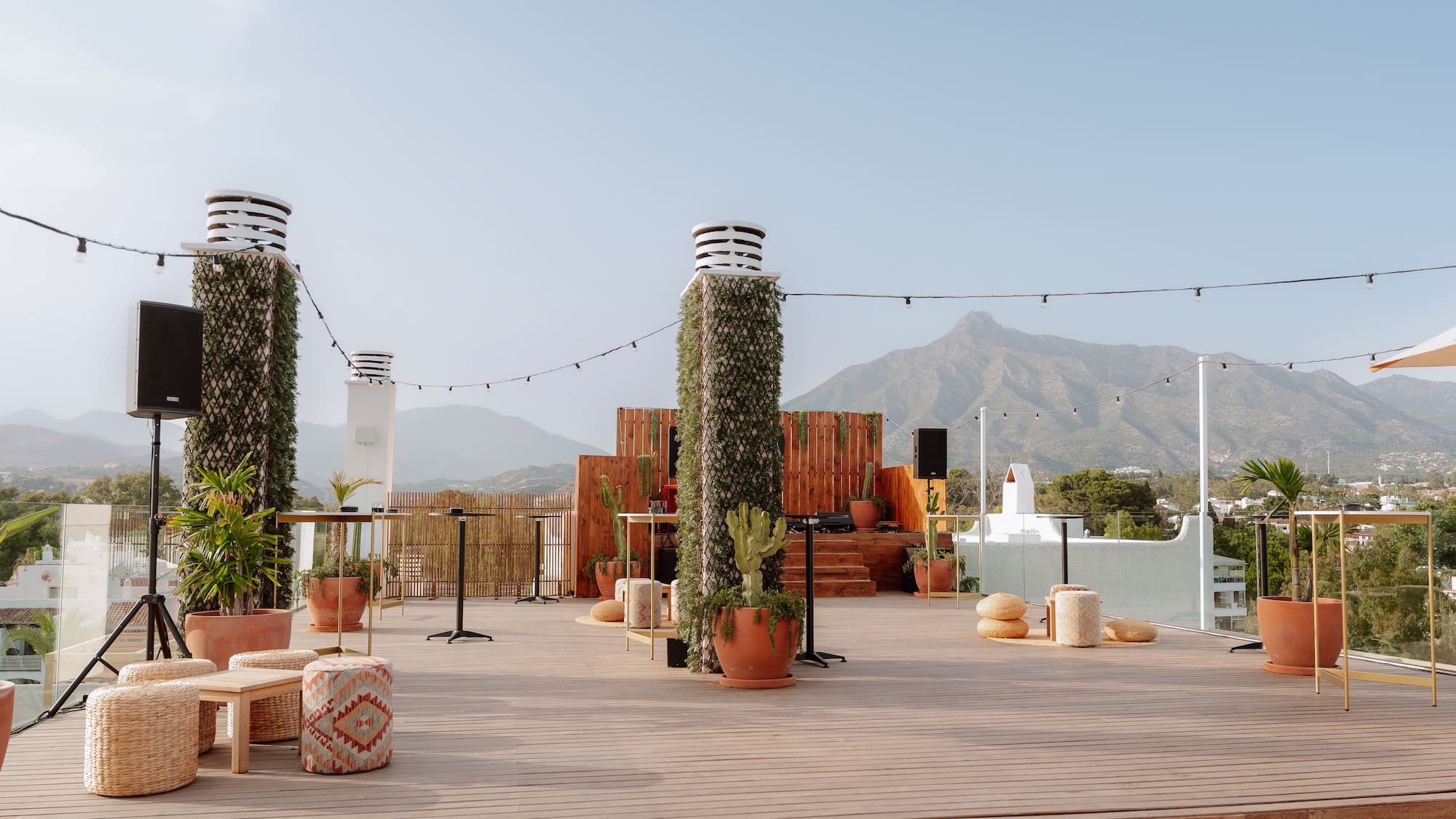 Outdoor rooftop terrace with stage, lounge seating, and mountain views.