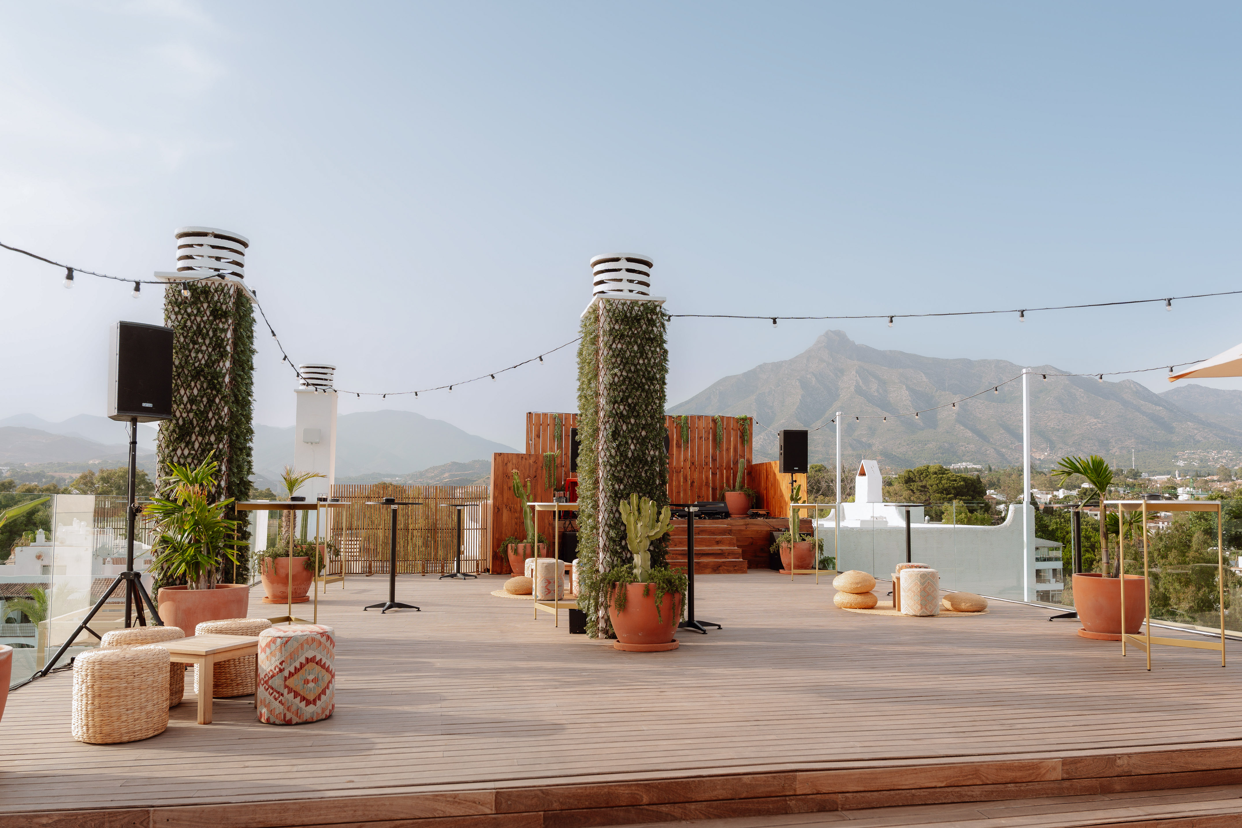 Outdoor rooftop terrace with stage, lounge seating, and mountain views.