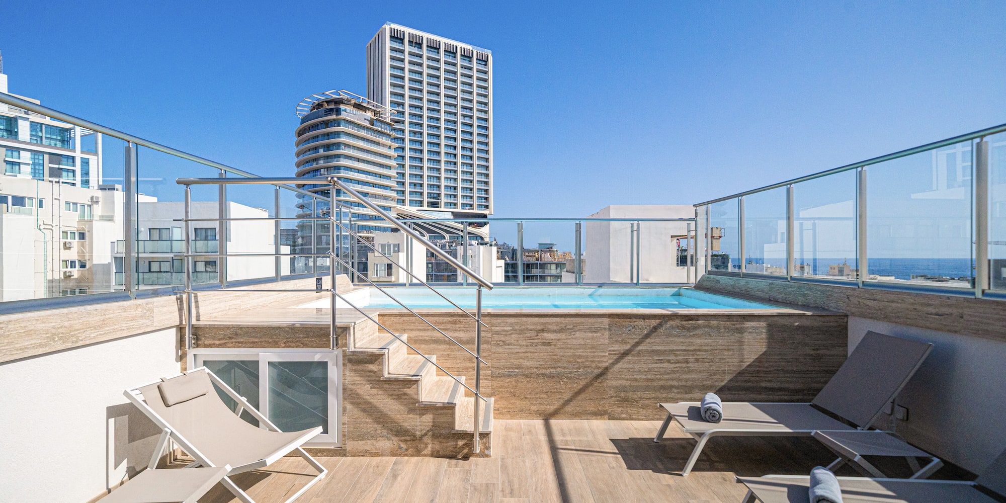 a deck with chairs and a pool on a rooftop