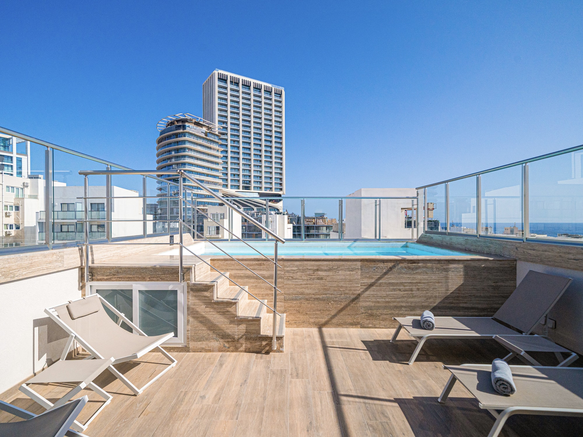 a deck with chairs and a pool on a rooftop