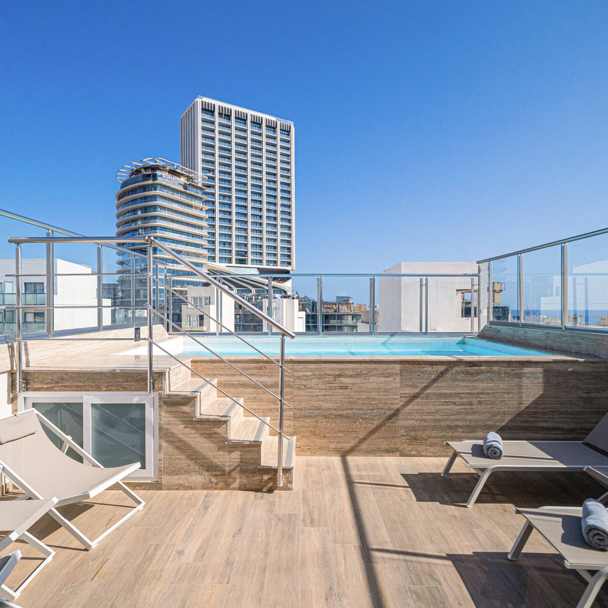 a deck with chairs and a pool on a rooftop