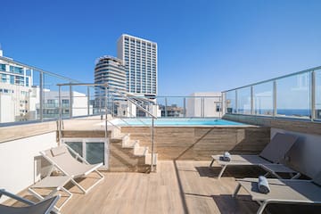 a deck with chairs and a pool on a rooftop