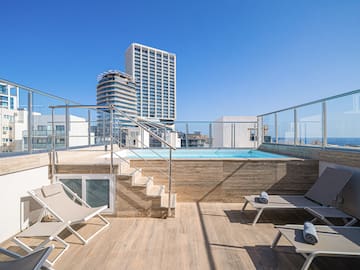 a deck with chairs and a pool on a rooftop