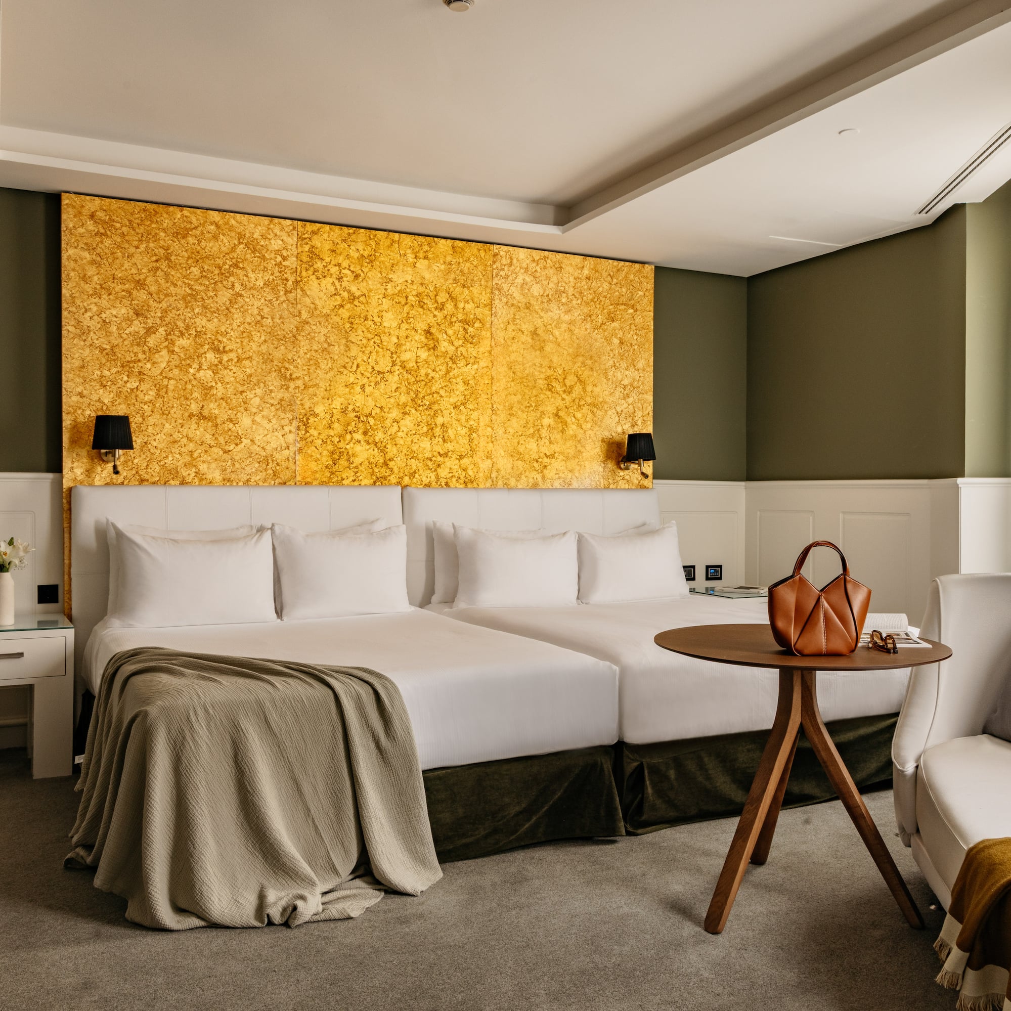 Habitación hotel de lujo con camas dobles, cabecero dorado y decoración verde oliva.