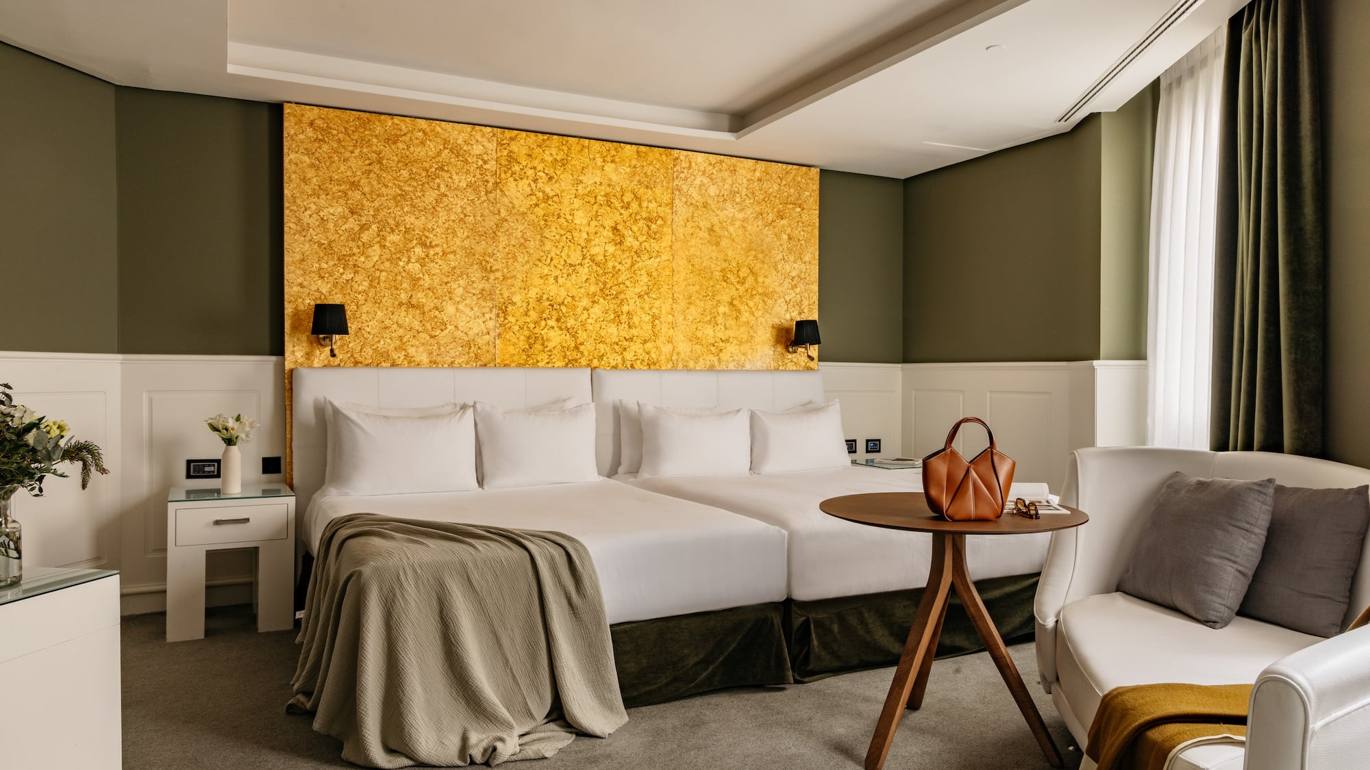 Habitación hotel de lujo con camas dobles, cabecero dorado y decoración verde oliva.