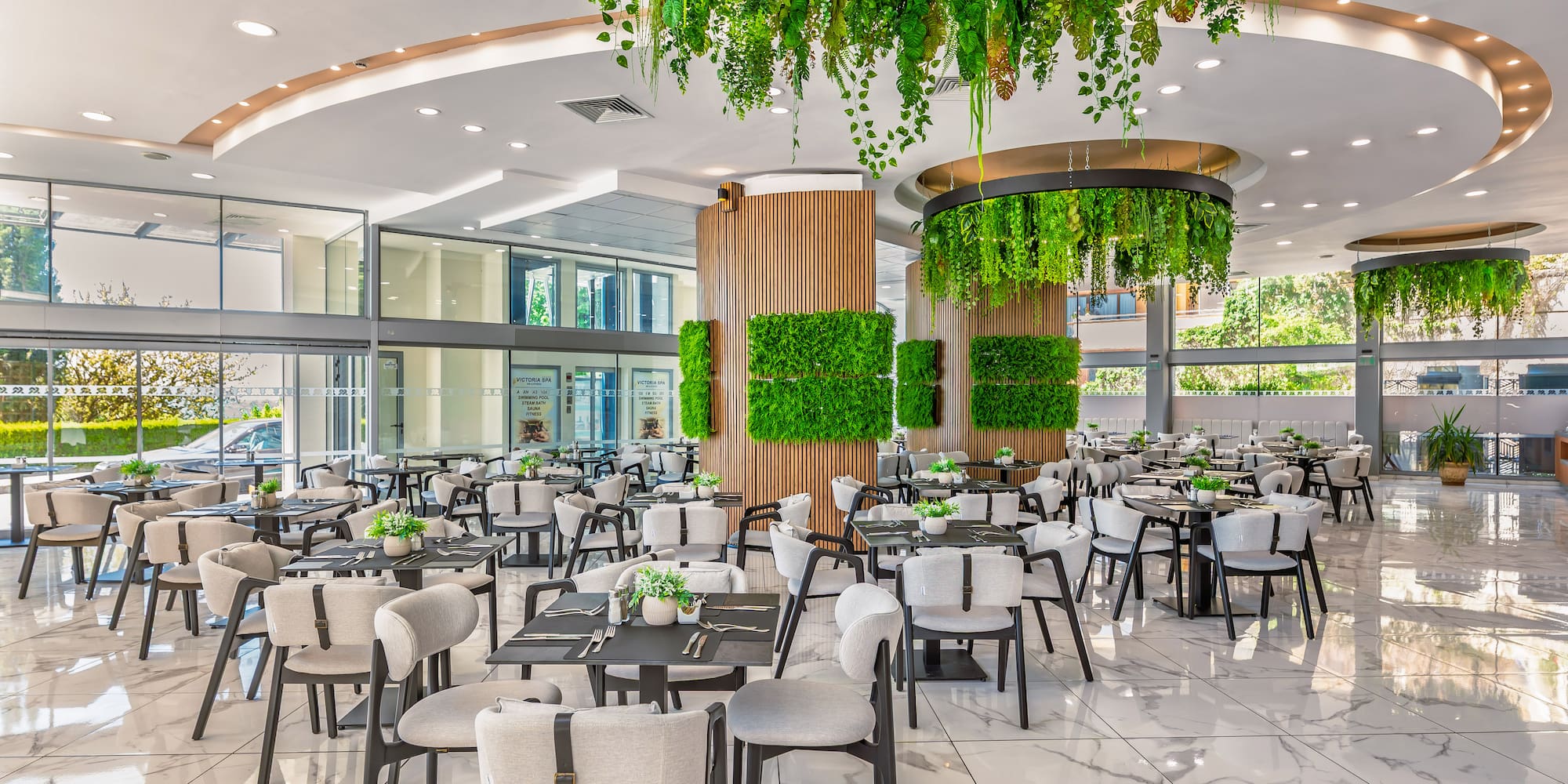 Modern biophilic restaurant with hanging green plants, green walls, and marble floor.