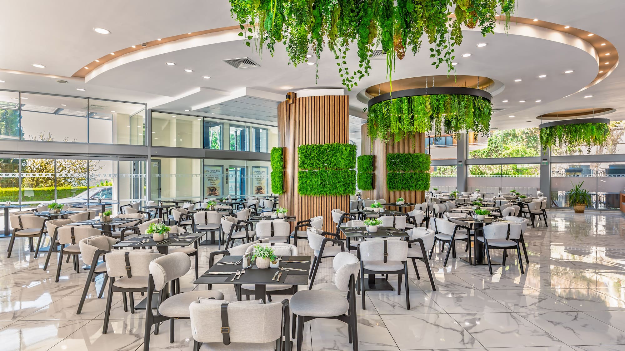 Modern biophilic restaurant with hanging green plants, green walls, and marble floor.