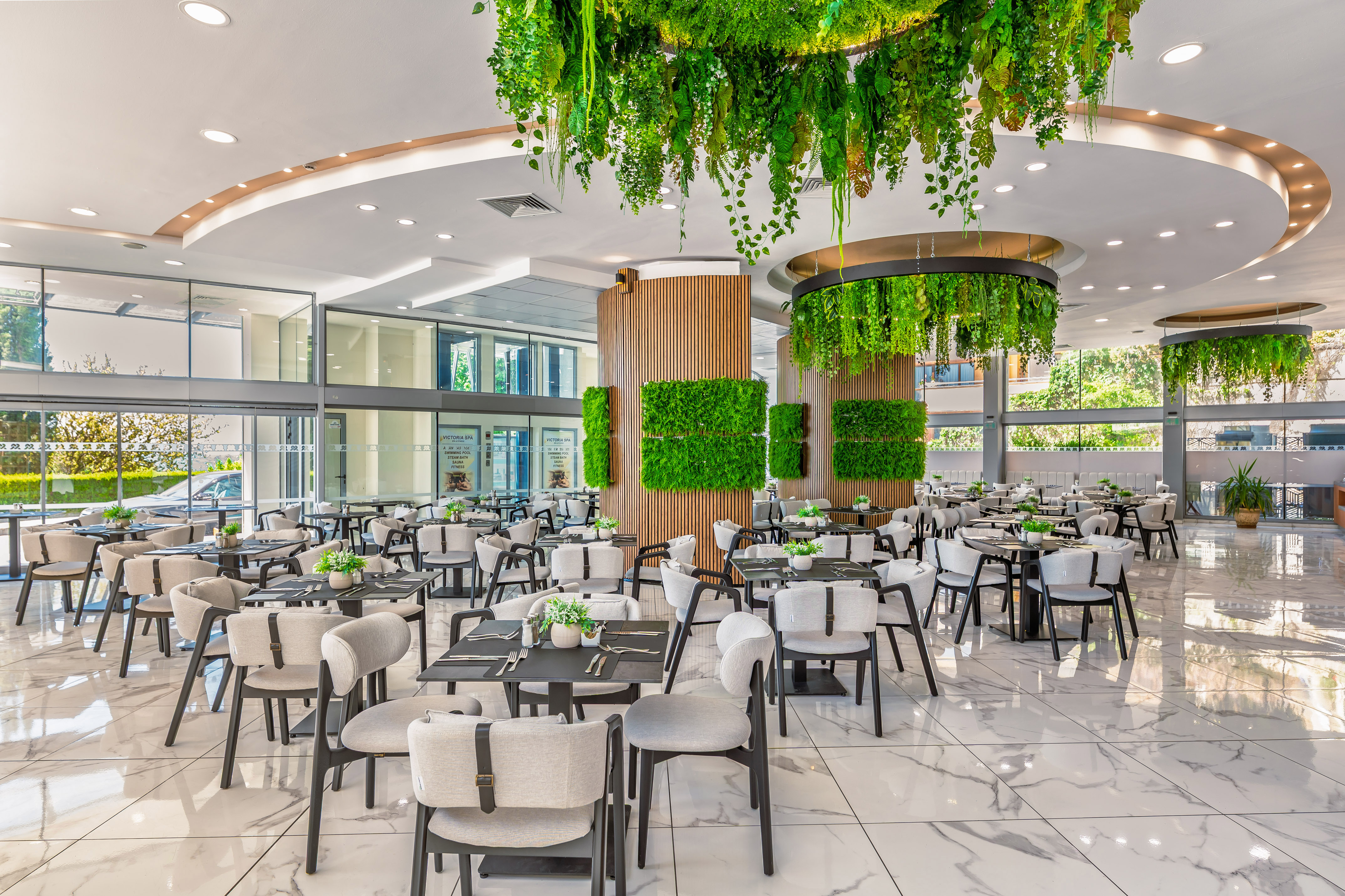 Modern biophilic restaurant with hanging green plants, green walls, and marble floor.