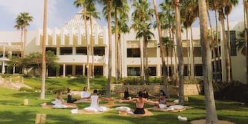 a group of people sitting on mats in a park
