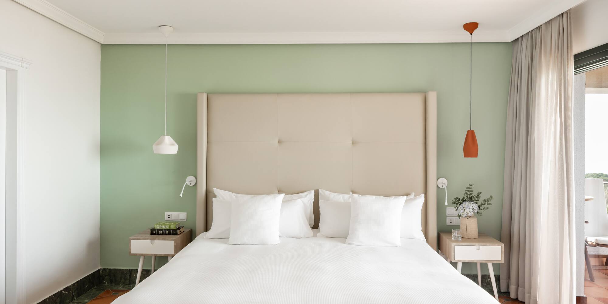 a bed with white pillows and a green wall