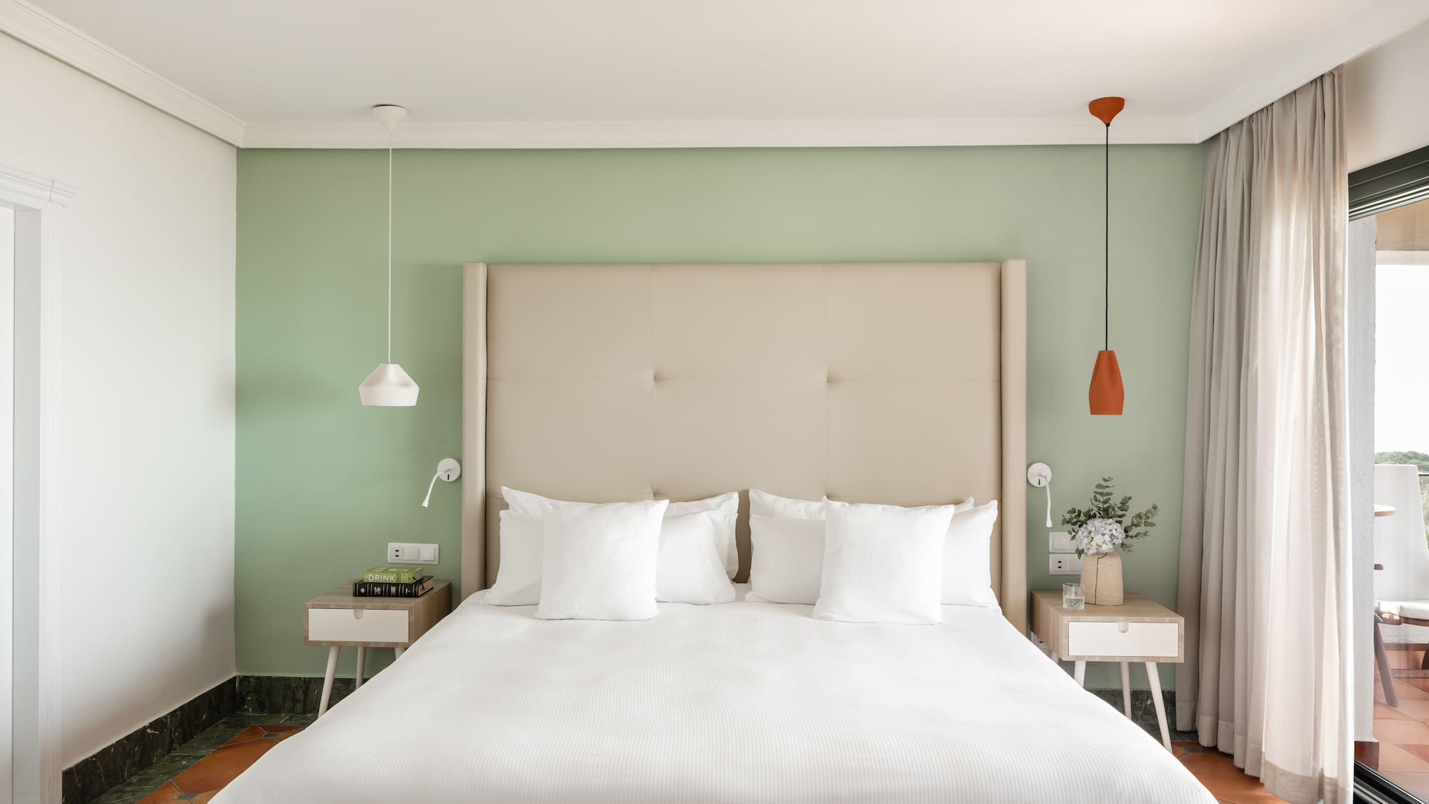 a bed with white pillows and a green wall