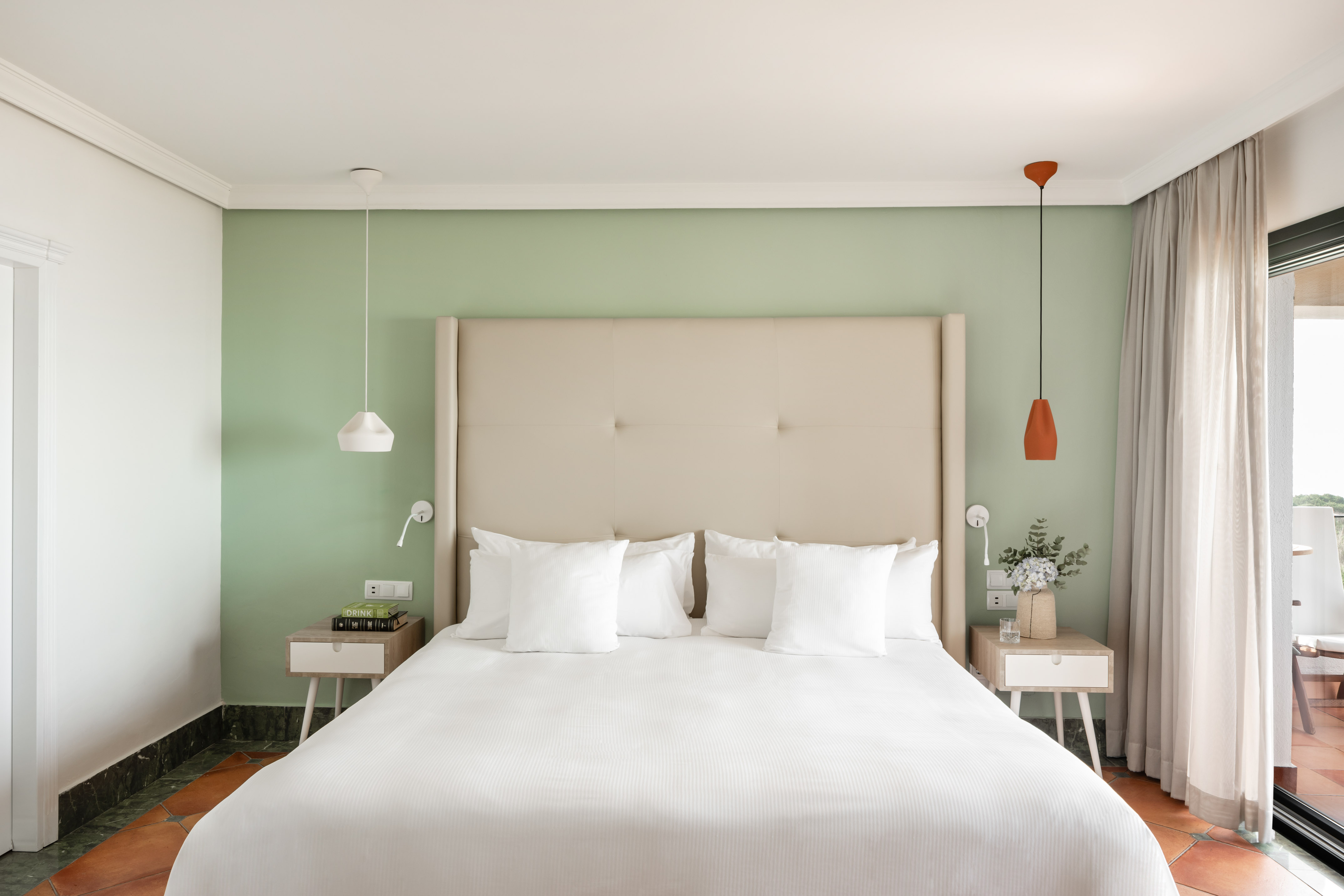 a bed with white pillows and a green wall