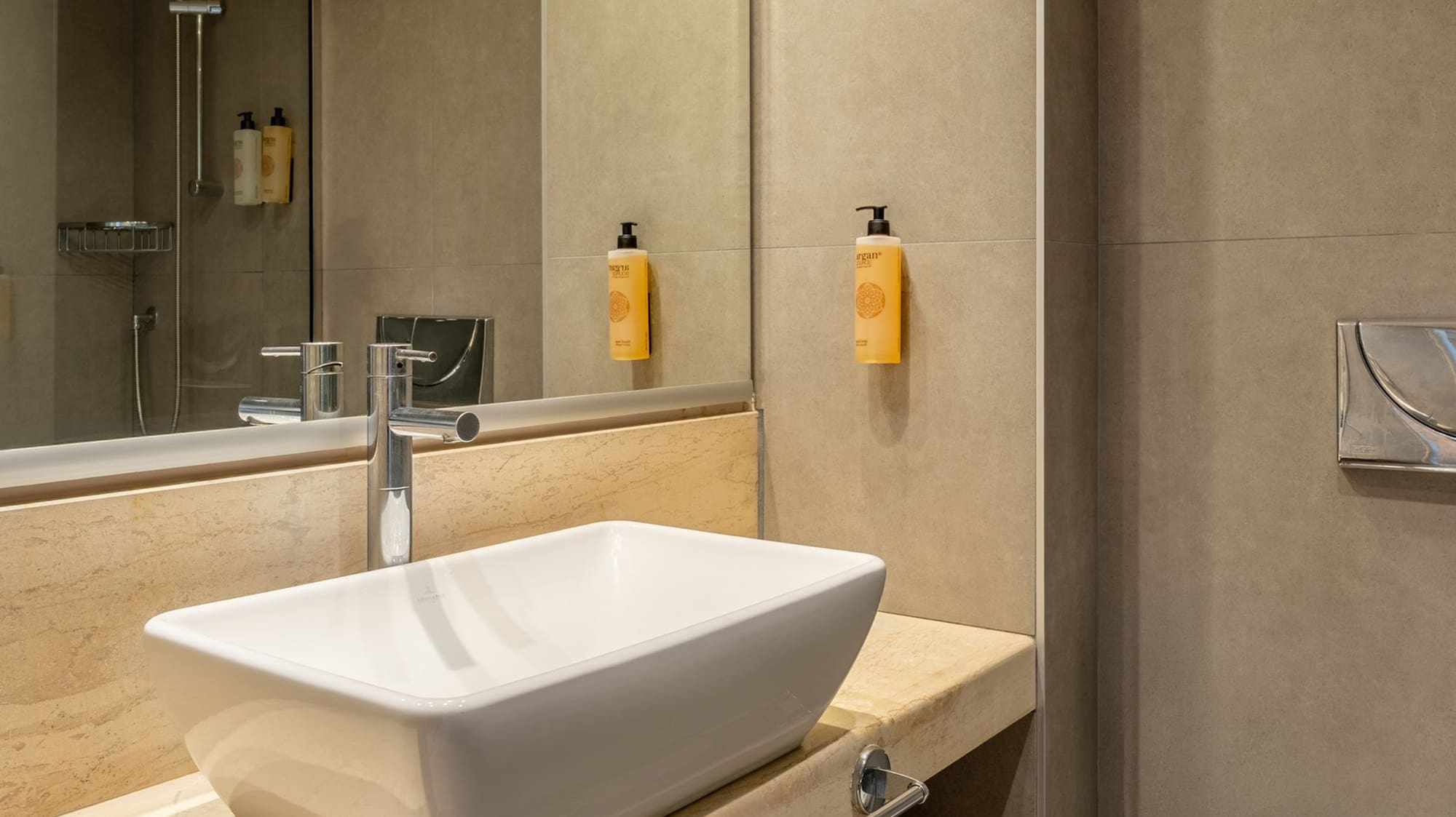 Modern bathroom with white vessel sink, marble vanity, shower, and toilet.