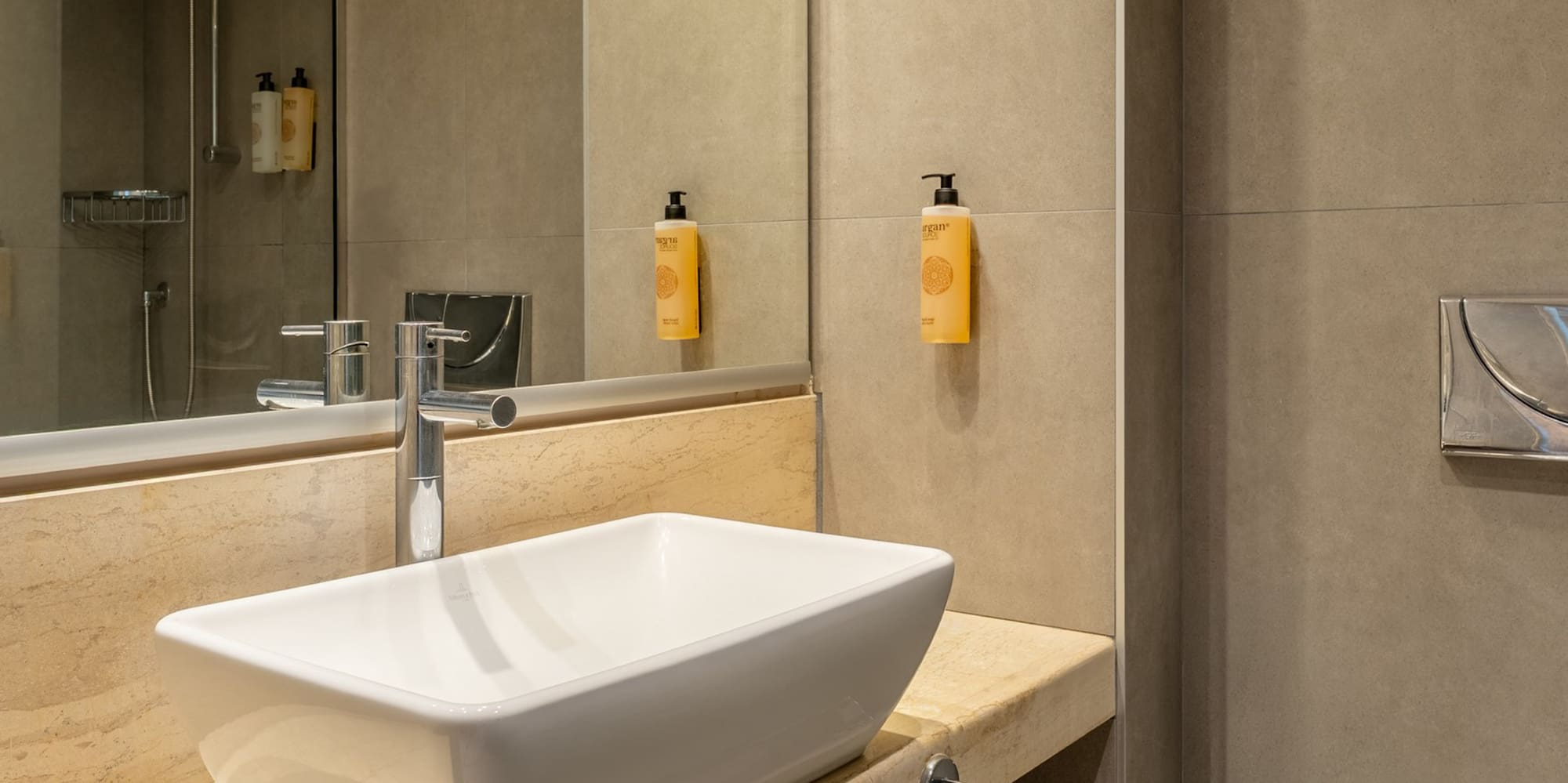 Modern bathroom with white vessel sink, marble vanity, shower, and toilet.