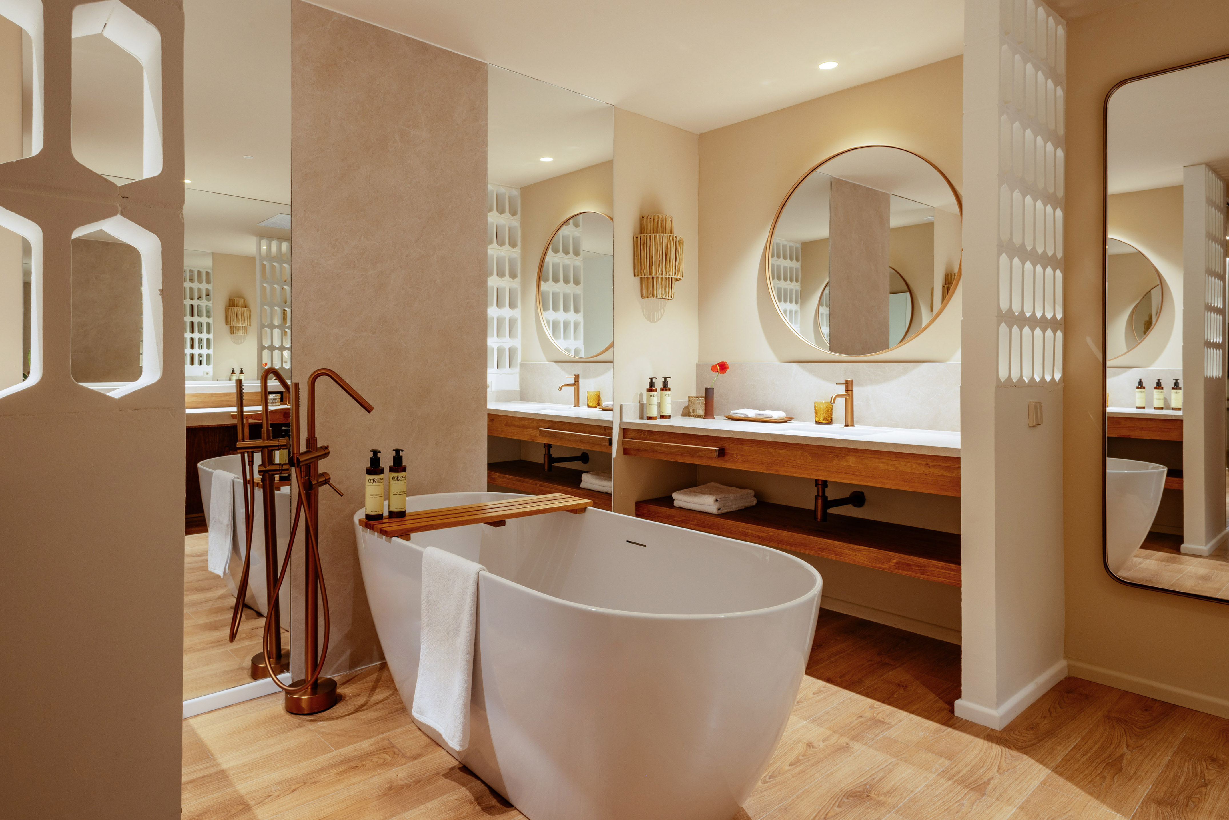 Modern spa bathroom with freestanding tub, dual vanity, and copper fixtures.
