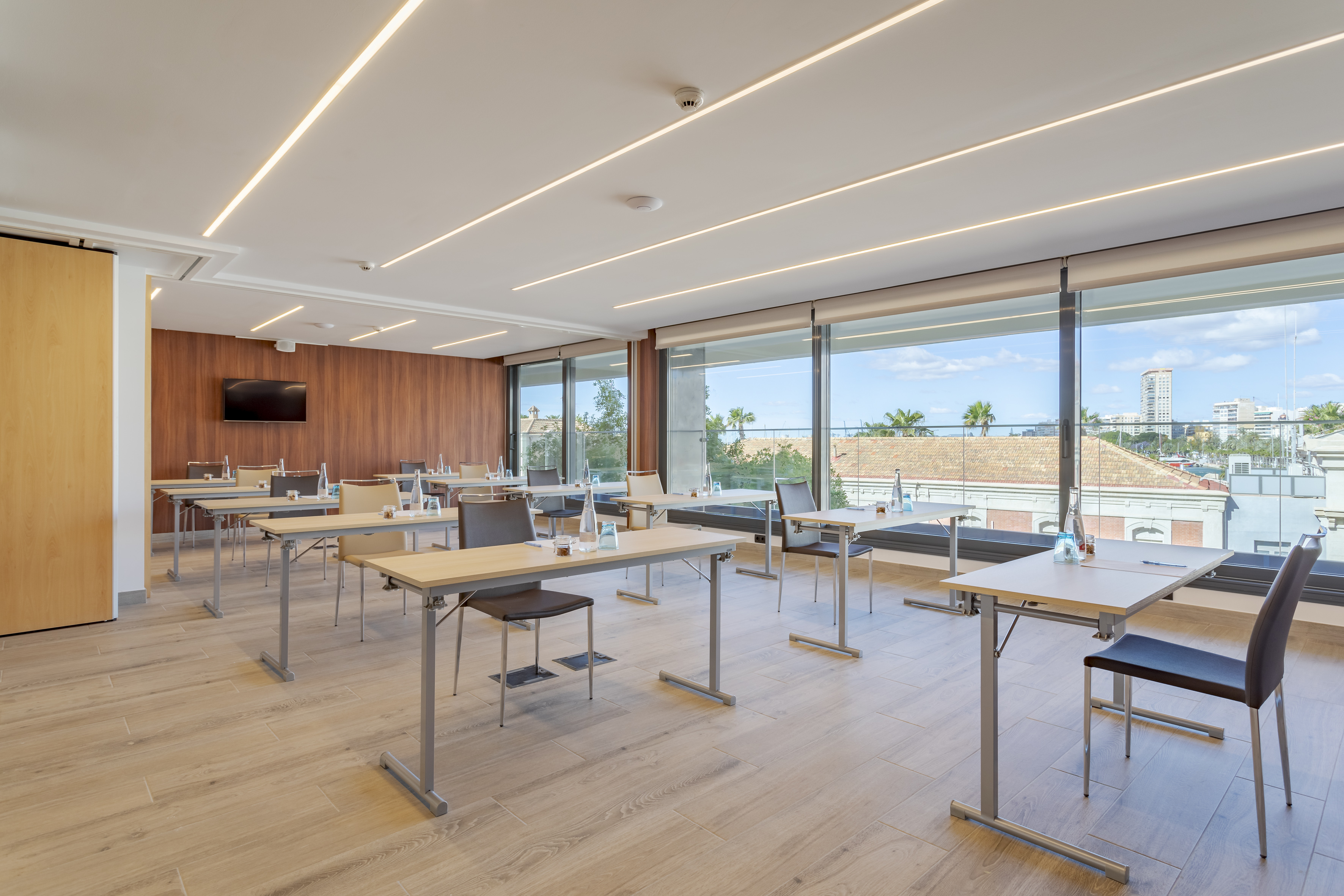 Modern meeting room with individual tables, large windows, and city view.
