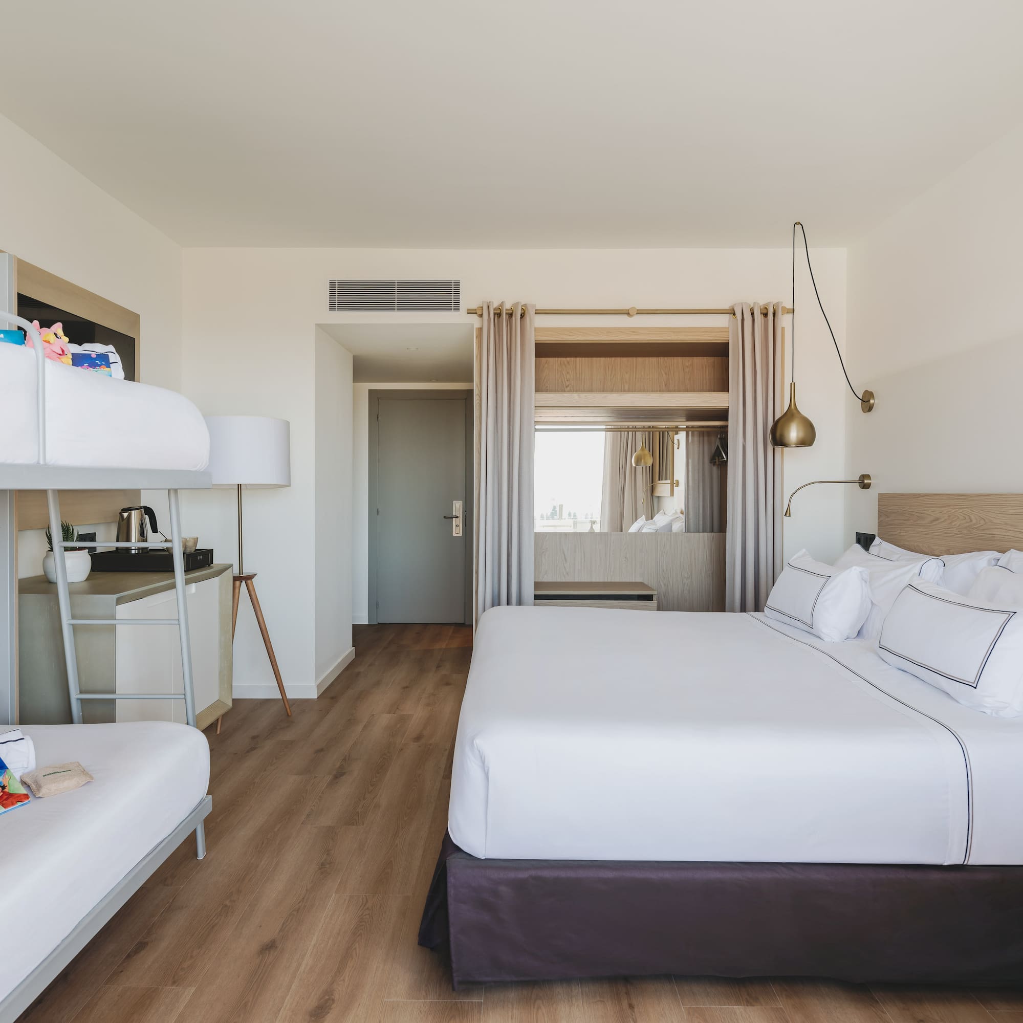 Habitación familiar de hotel con cama king, literas y diseño moderno.