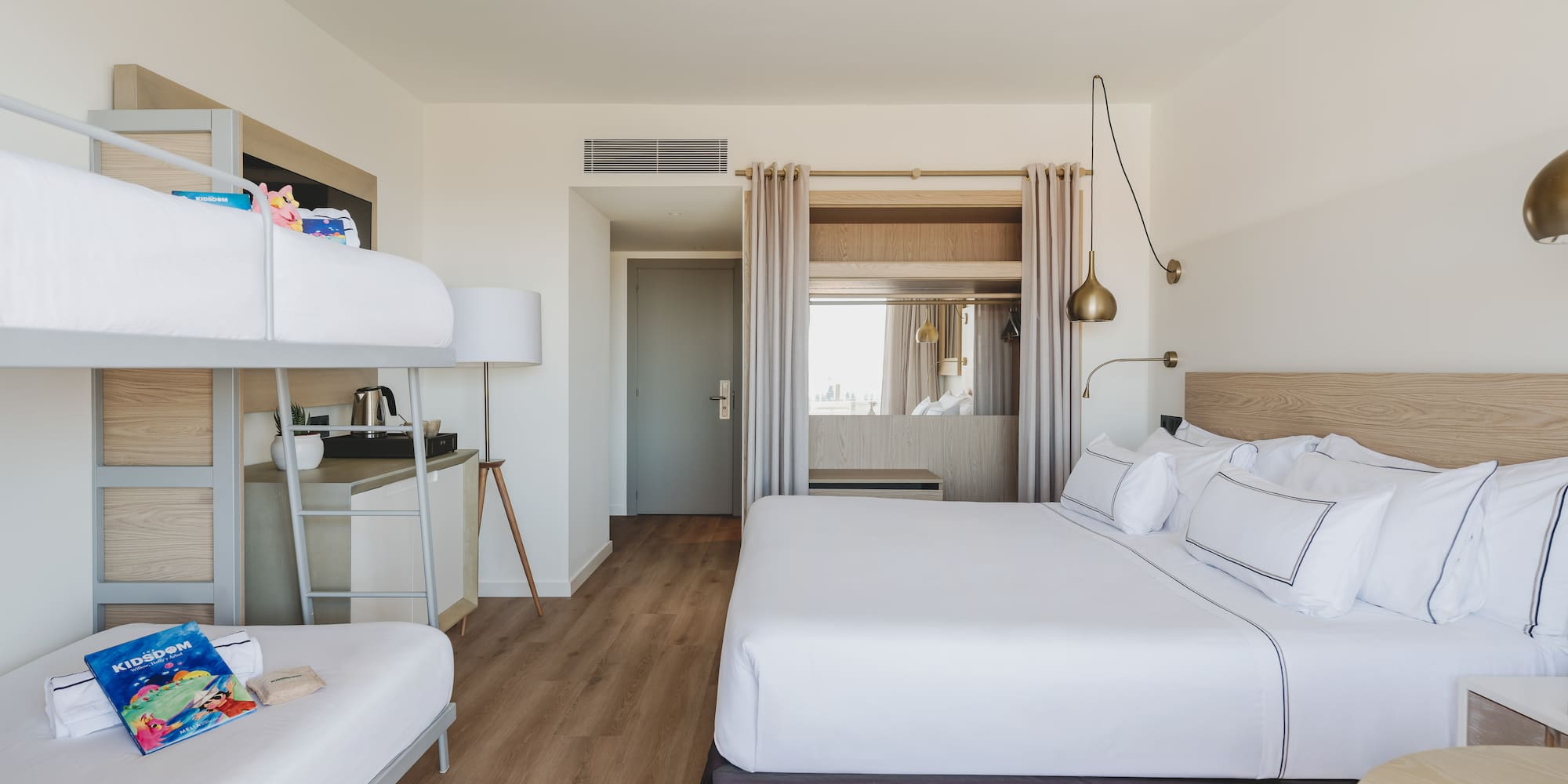 Habitación familiar de hotel con cama king, literas y diseño moderno.