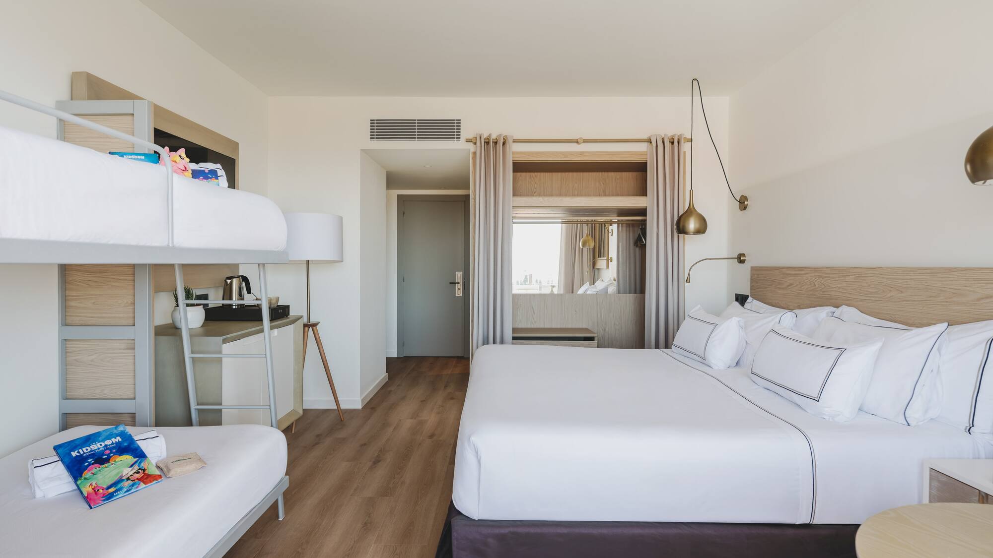 Habitación familiar de hotel con cama king, literas y diseño moderno.
