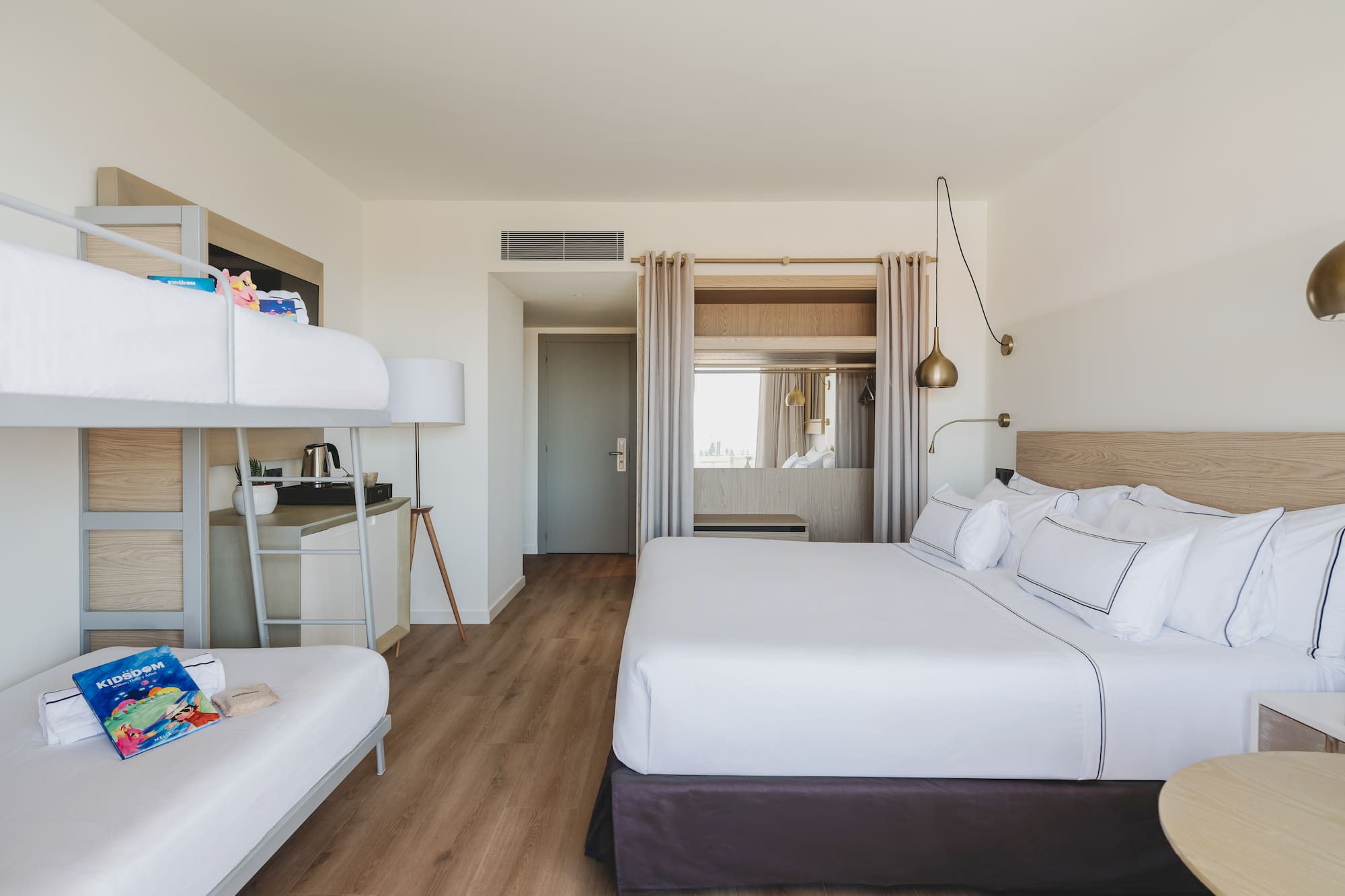 Habitación familiar de hotel con cama king, literas y diseño moderno.